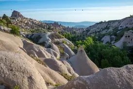 Weite Tuffsteinlandschaft mit Feenkaminen im Taubental und Blick auf den Burgberg von Uchisar in Kappadokien.