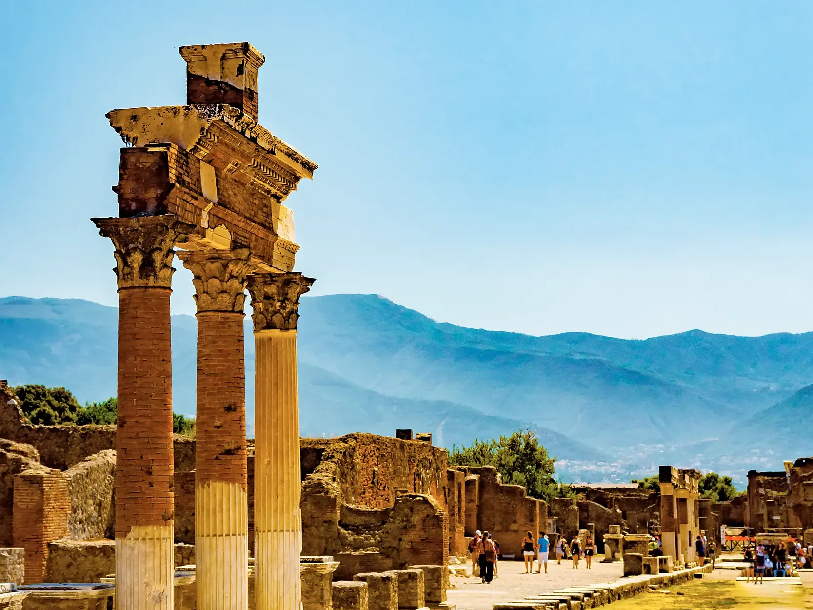 Korinthische Säulen in der Ausgrabungsstätte von Pompeji bei einer Studiosus Studienreise mit Blick auf die Berge am Golf von Neapel.