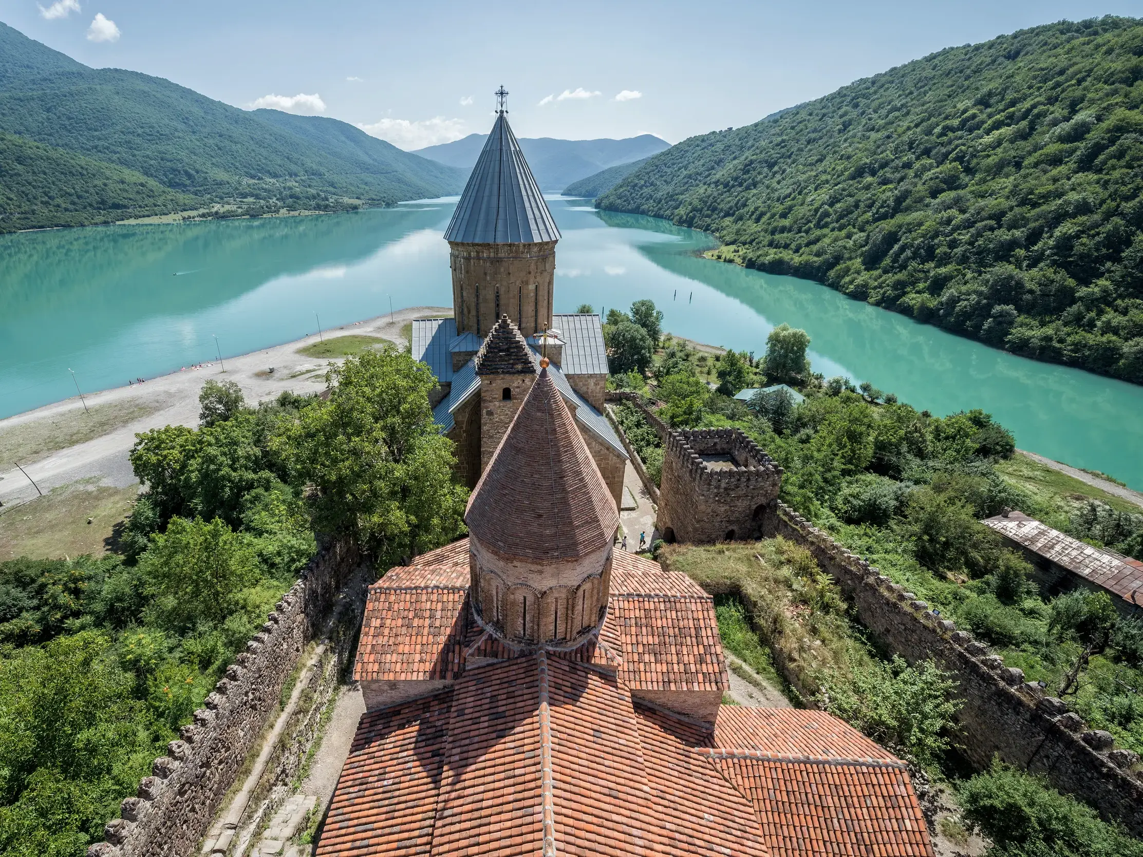 Die historische Festung Ananuri am Ufer des türkisgrünen Schinwali-Stausees, umgeben von den bewaldeten Bergen Georgiens.