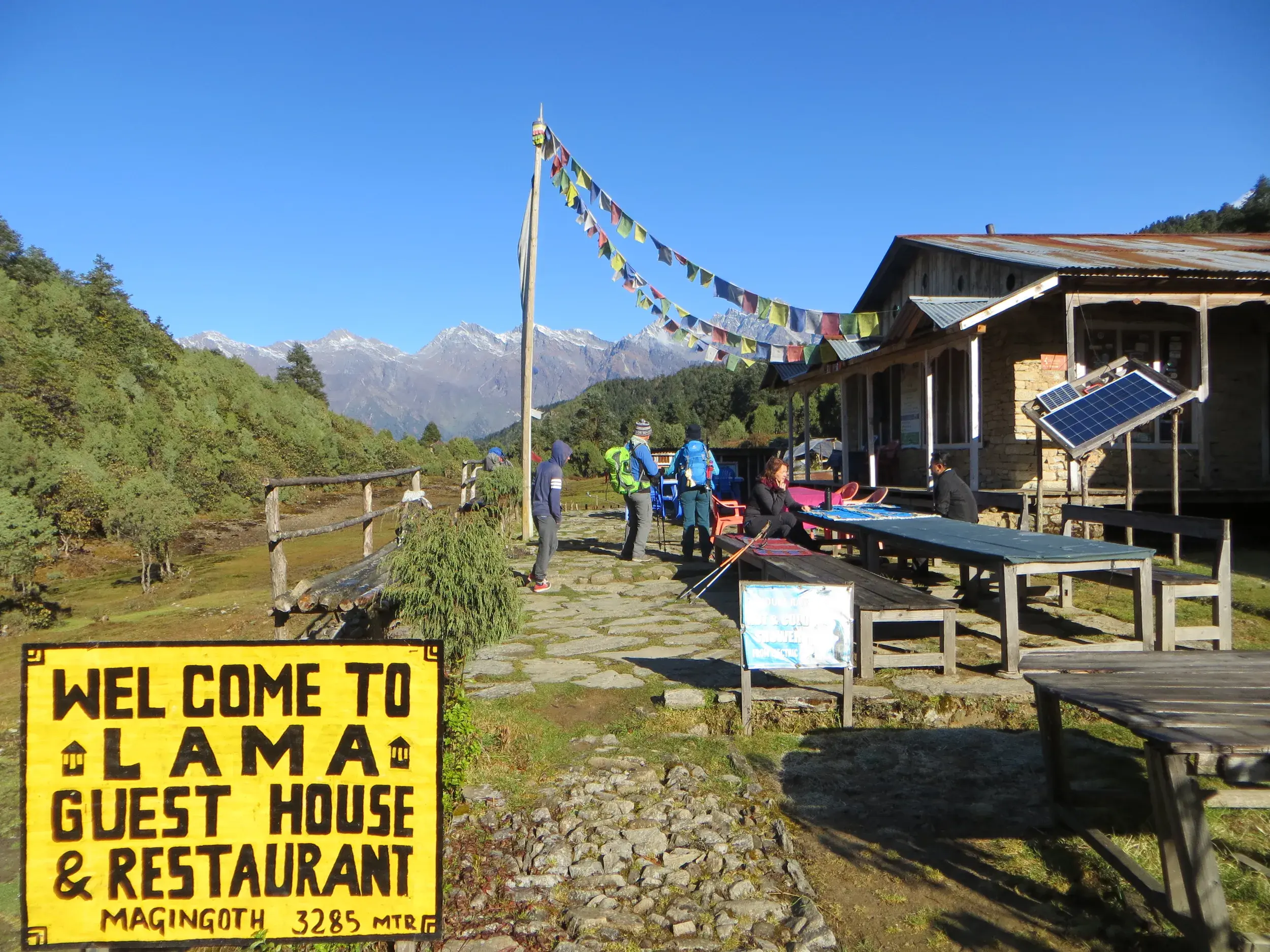 Wandergruppe macht eine Pause am Lama Guest House in Mangengoth vor dem Panorama des Jugal Himal in Nepal.