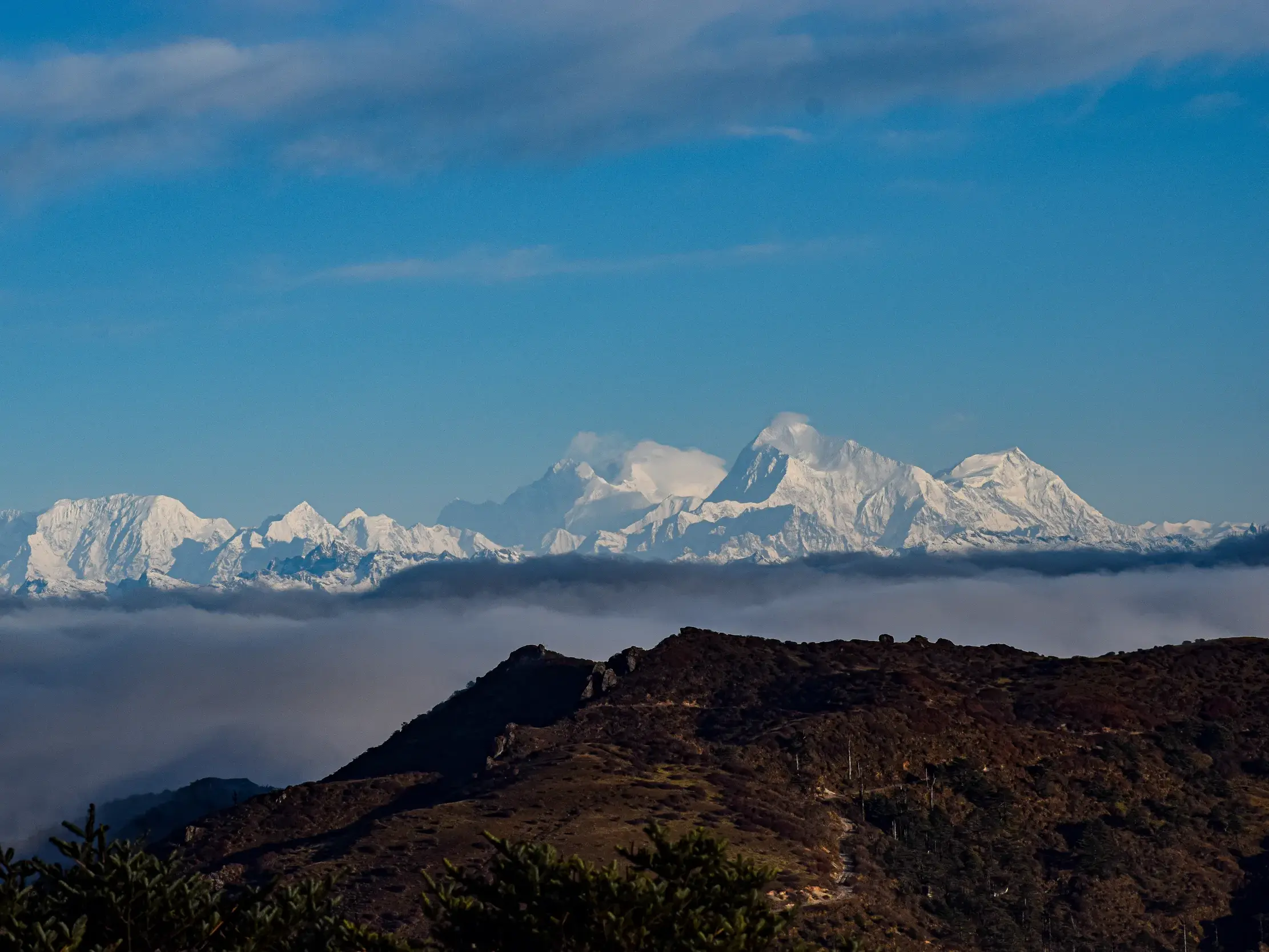 Panoramablick beim Trekking auf die schneebedeckten Gipfel des Kangchendzönga-Massivs im Himalaya über den Wolken.