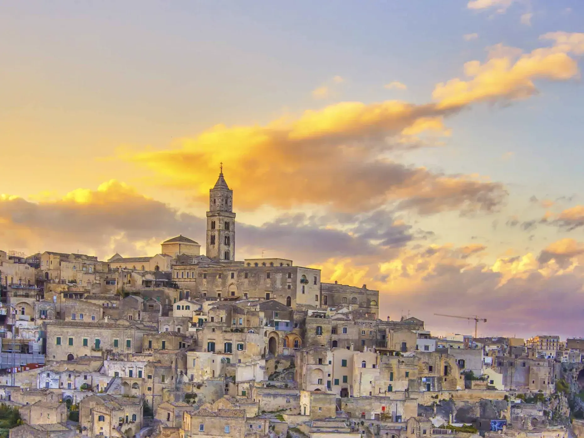 Die historischen Höhlensiedlungen, die Sassi di Matera, im warmen Abendlicht mit der Kathedrale im Hintergrund.