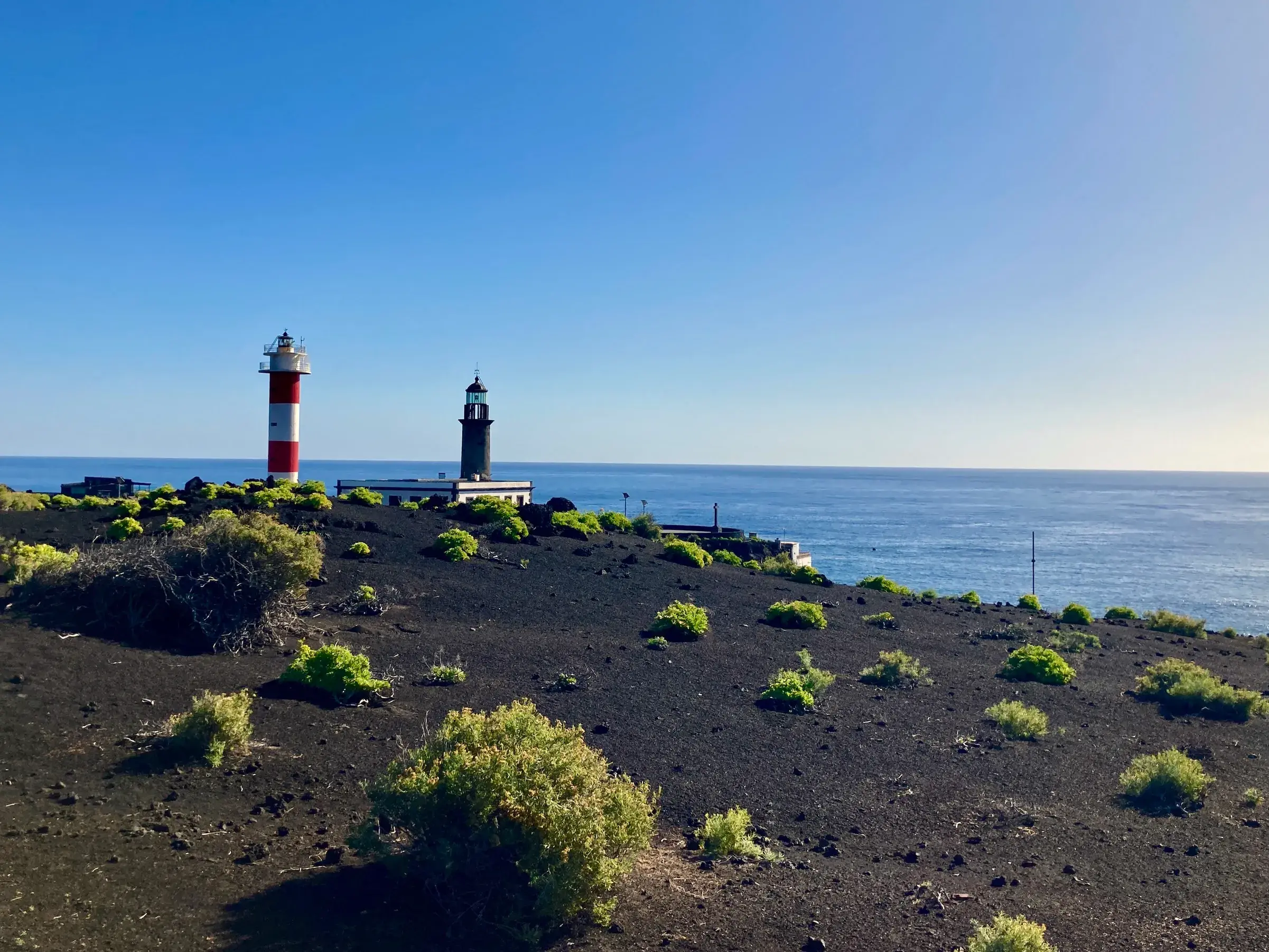 Die beiden Leuchttürme von Fuencaliente an La Palmas Südspitze inmitten einer schwarzen Vulkanlandschaft direkt am Meer.