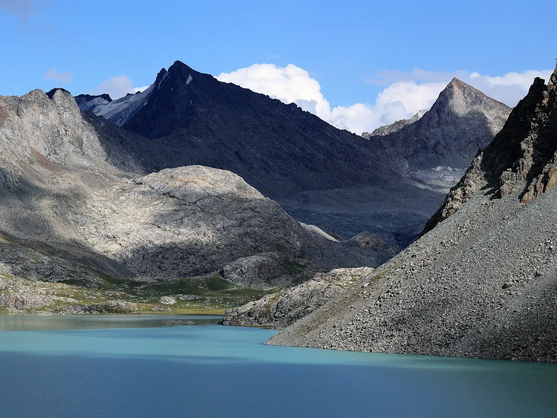 Türkisblauer Bergsee Alaköl umgeben von schroffen, felsigen Gipfeln im Terskej-Alatau-Gebirge in Kirgistan.