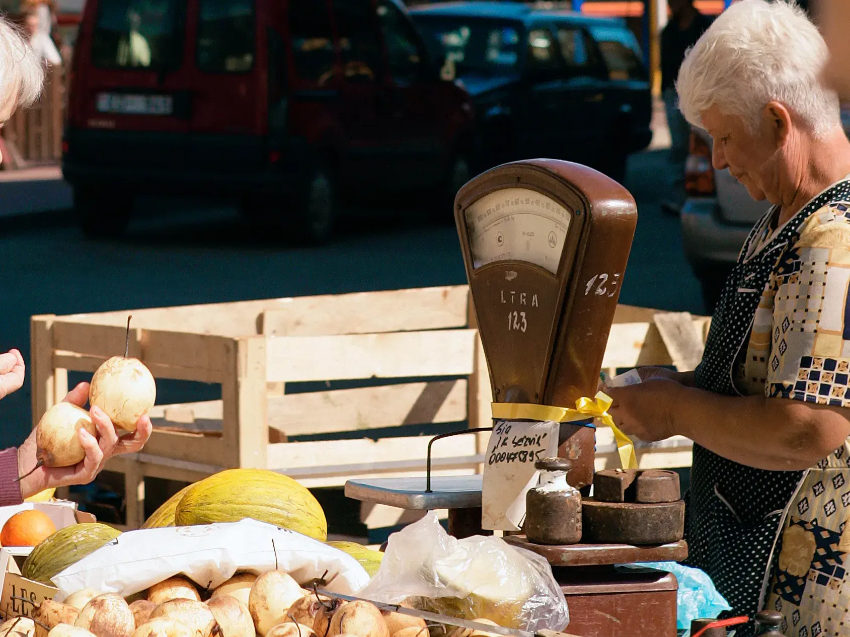 Auf einem Markt in Riga wiegt eine Verkäuferin frische Birnen für eine Kundin auf einer traditionellen Waage.