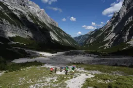 Eine Hauser-Trekkinggruppe wandert auf einem Schotterpfad durch das weite, sonnige Reintal in Richtung Zugspitze.