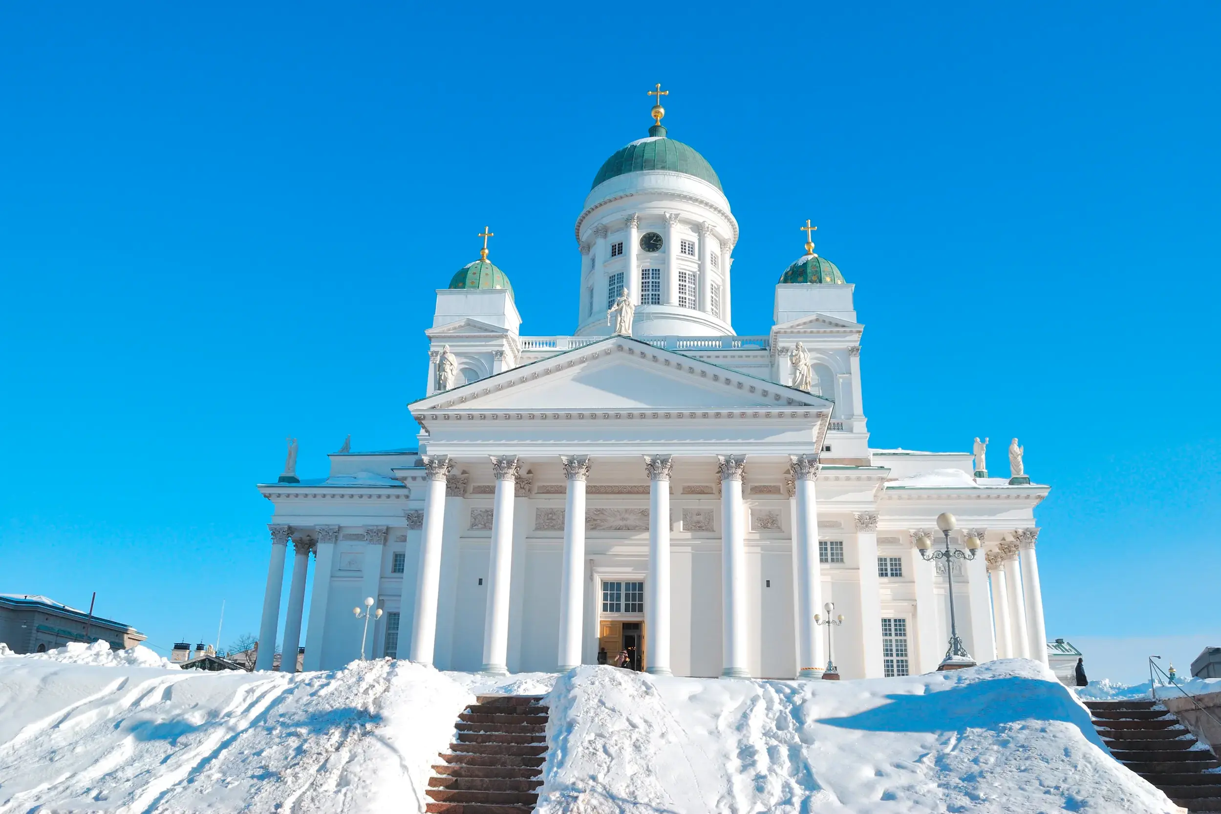 Der weiße Dom von Helsinki mit seinen grünen Kuppeln auf dem Senatsplatz, die große Freitreppe ist tief verschneit.