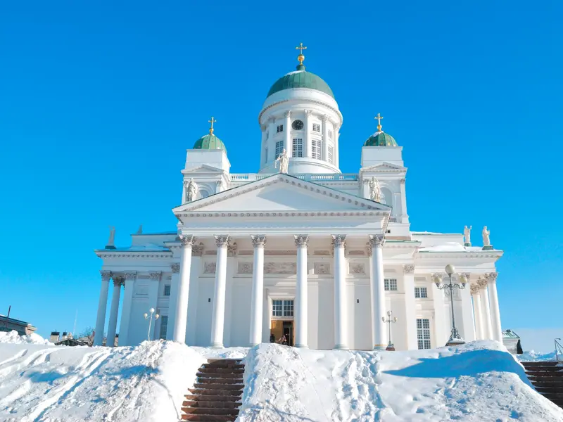 Der weiße Dom von Helsinki mit seinen grünen Kuppeln auf dem Senatsplatz, die große Freitreppe ist tief verschneit.