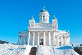 Der weiße Dom von Helsinki mit seinen grünen Kuppeln auf dem Senatsplatz, die große Freitreppe ist tief verschneit.