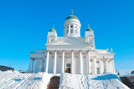 Der weiße Dom von Helsinki mit seinen grünen Kuppeln auf dem Senatsplatz, die große Freitreppe ist tief verschneit.