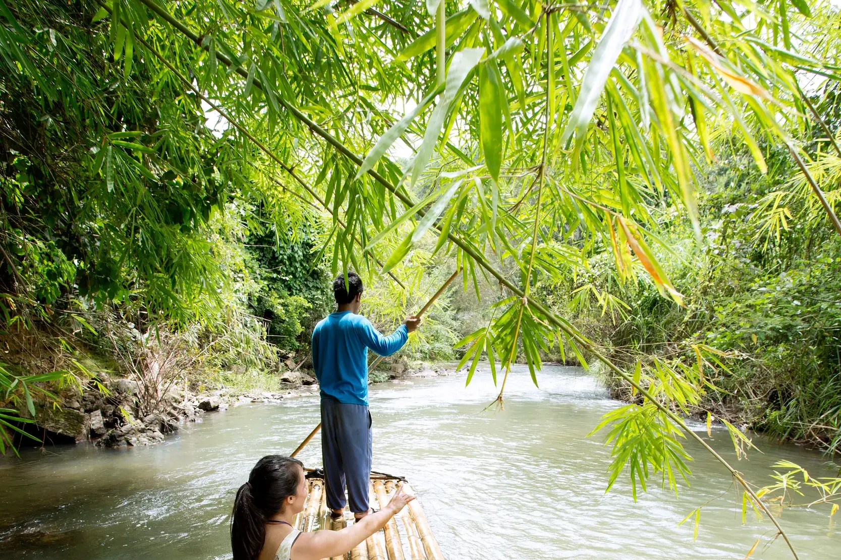Junge Leute auf einer abenteuerlichen Bambusfloßfahrt auf dem River Kwai während einer geführten Rundreise durch Thailand.