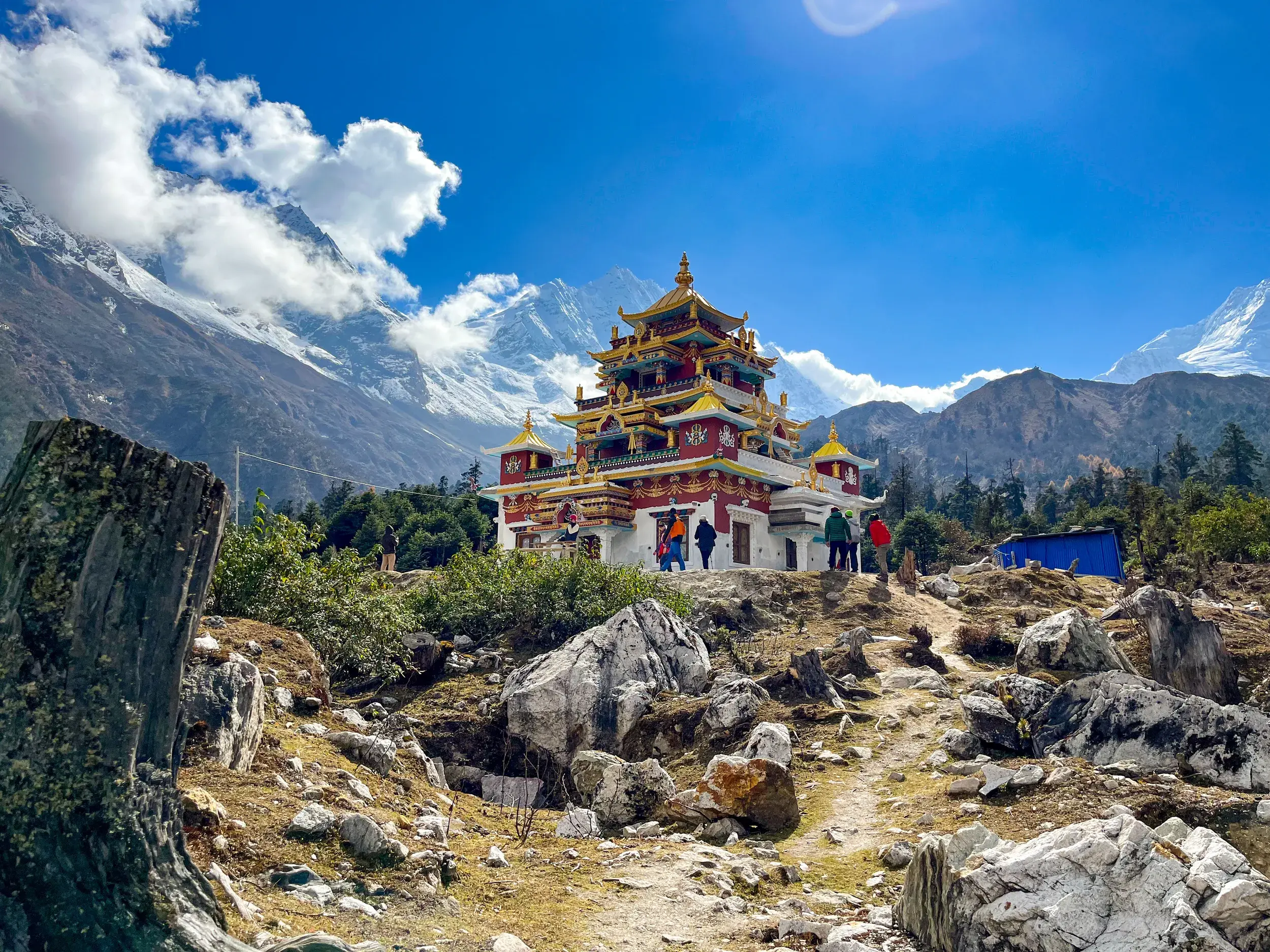 Eine Wandergruppe besichtigt die Punggen Gompa in Nepal, im Hintergrund die schneebedeckten Gipfel des Manaslu-Massivs.