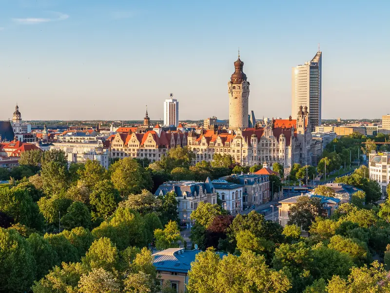 Blick über die grüne Stadtkulisse von Leipzig mit dem Neuen Rathaus und dem modernen City-Hochhaus.