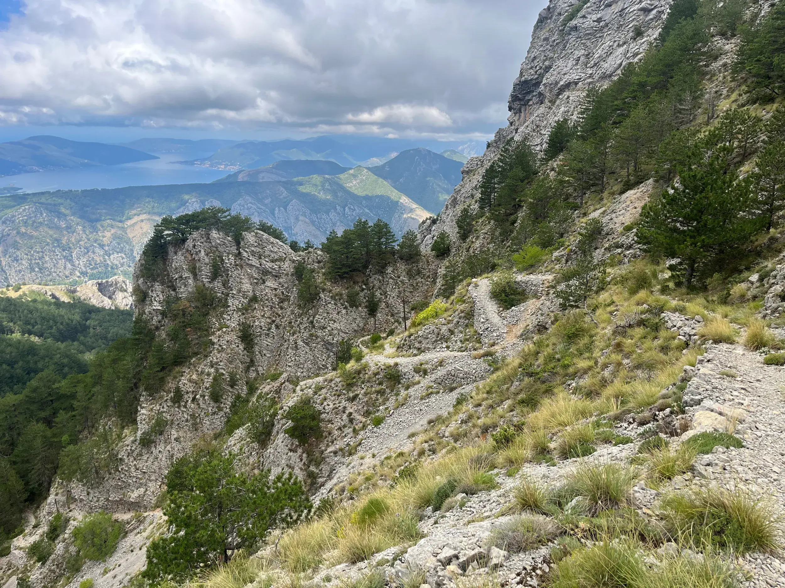 Ein schmaler Wanderpfad führt in Serpentinen durch die Bergwelt Montenegros mit weitem Blick auf die Bucht von Kotor.