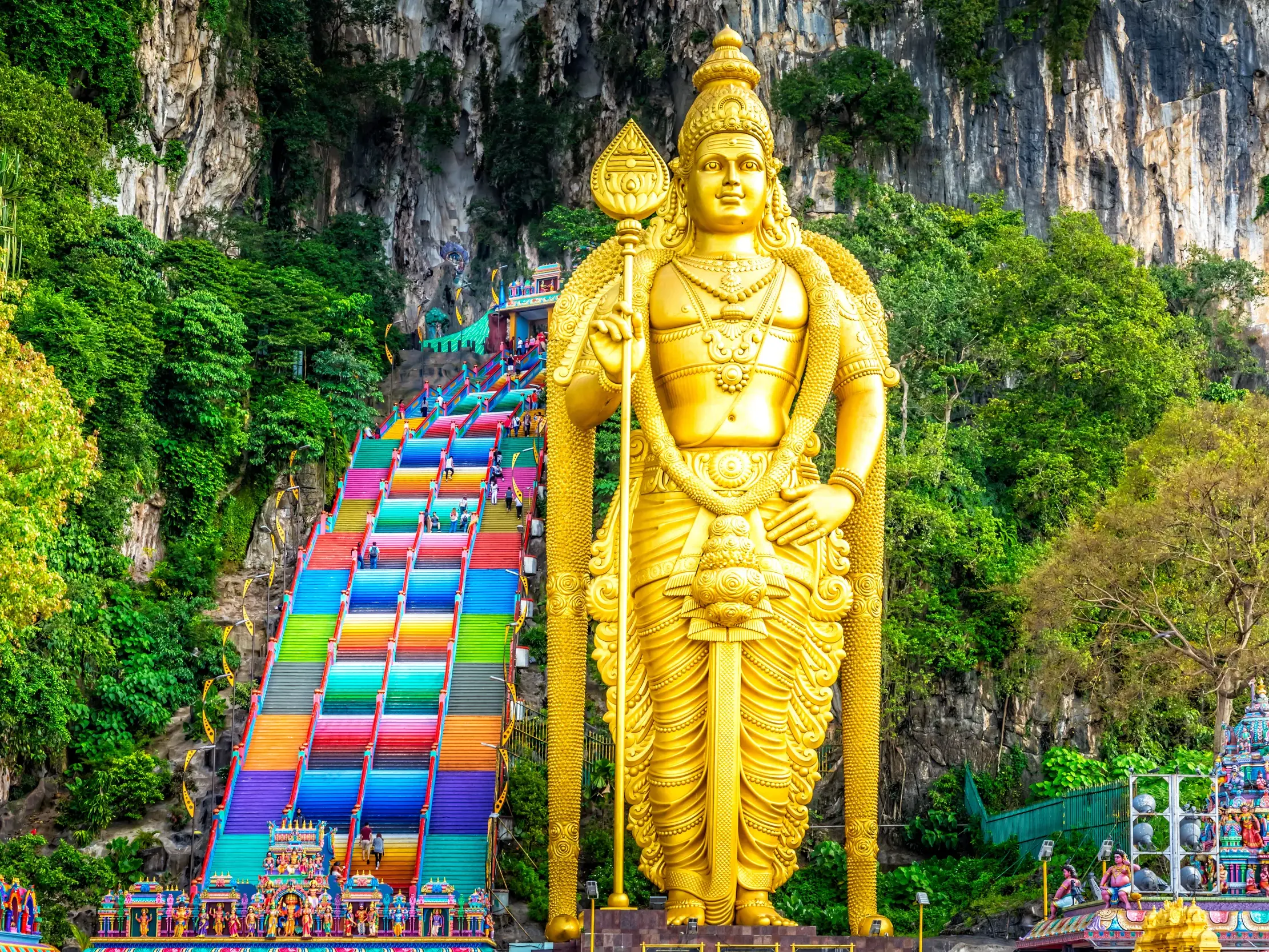 Goldene Statue des Hindugottes Murugan an der farbenfrohen Treppe zu den Batu-Höhlen, ein Höhepunkt der Studienreise in Malaysia.