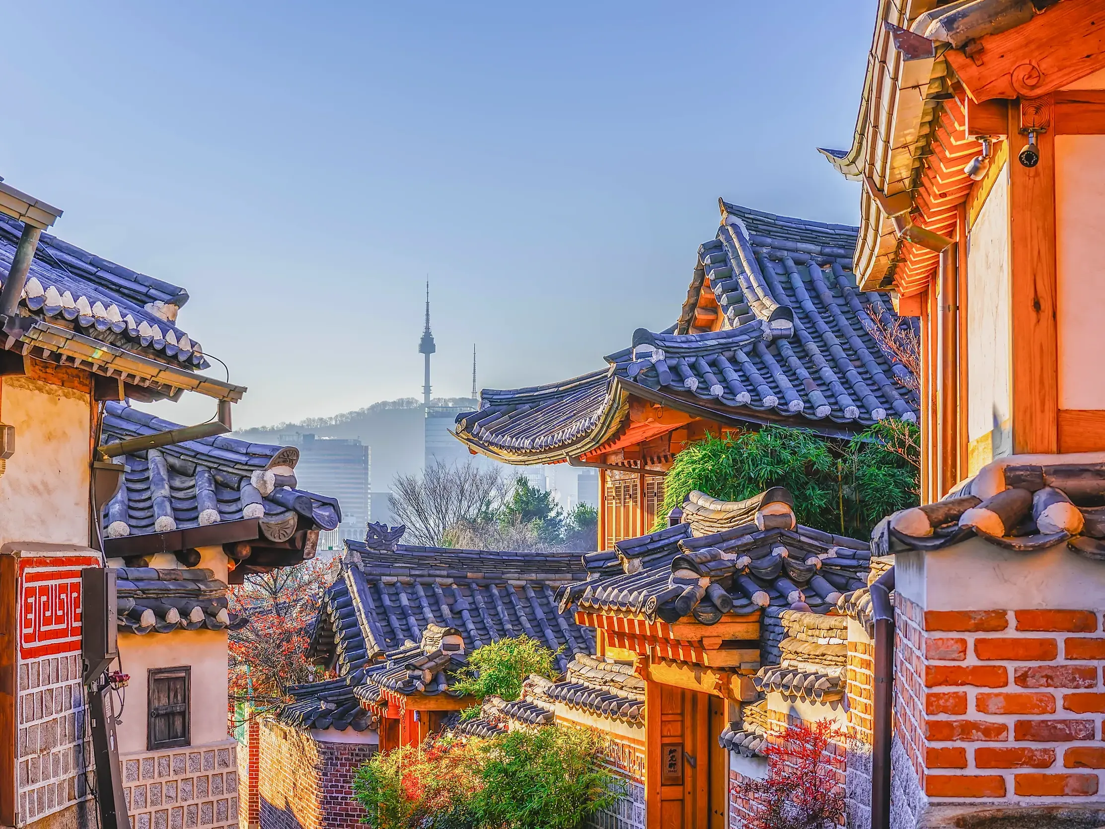 Blick über die traditionellen Ziegeldächer des Bukchon Hanok Village auf die moderne Skyline von Seoul mit dem N Seoul Tower.