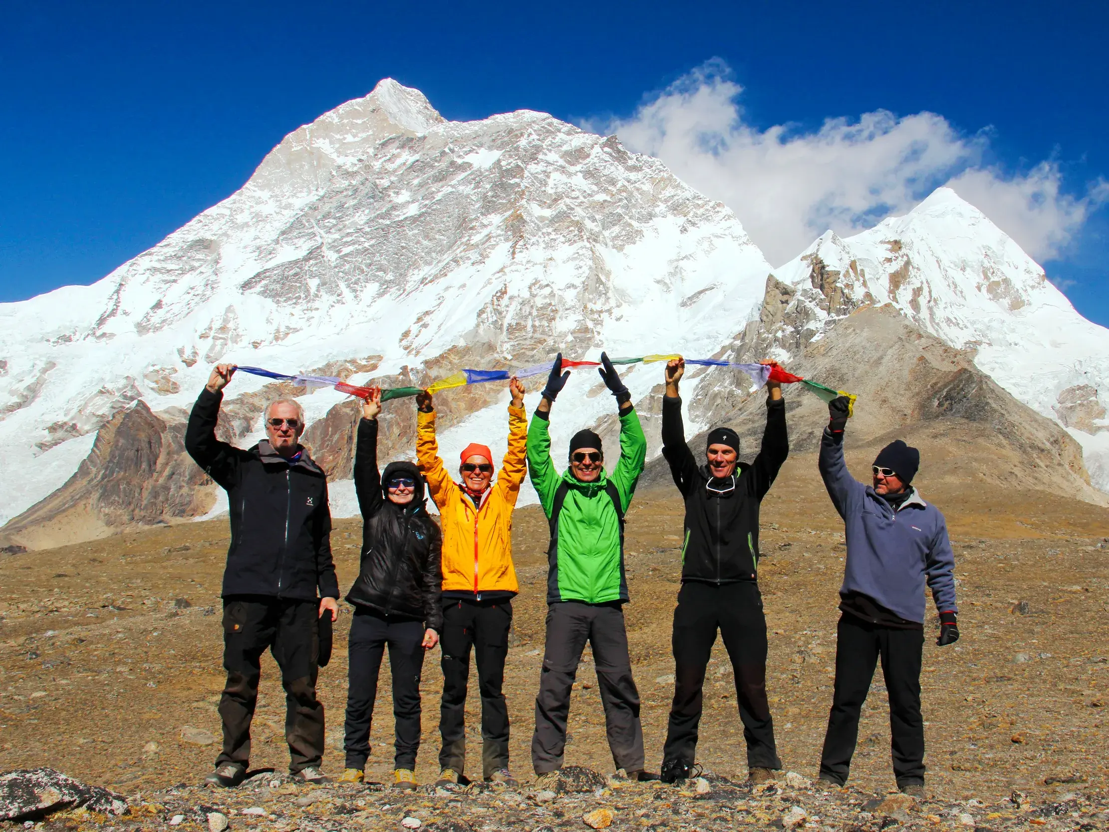 Eine Trekkinggruppe feiert ihre Ankunft im Makalu-Basislager mit Gebetsfahnen vor dem gewaltigen Gipfel des Makalu in Nepal.