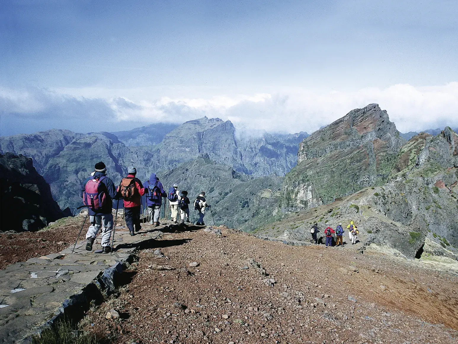 Eine Wandergruppe beim Trekking auf einem steinigen Gratweg im Zentralmassiv von Madeira, mit Blick auf schroffe Berggipfel.