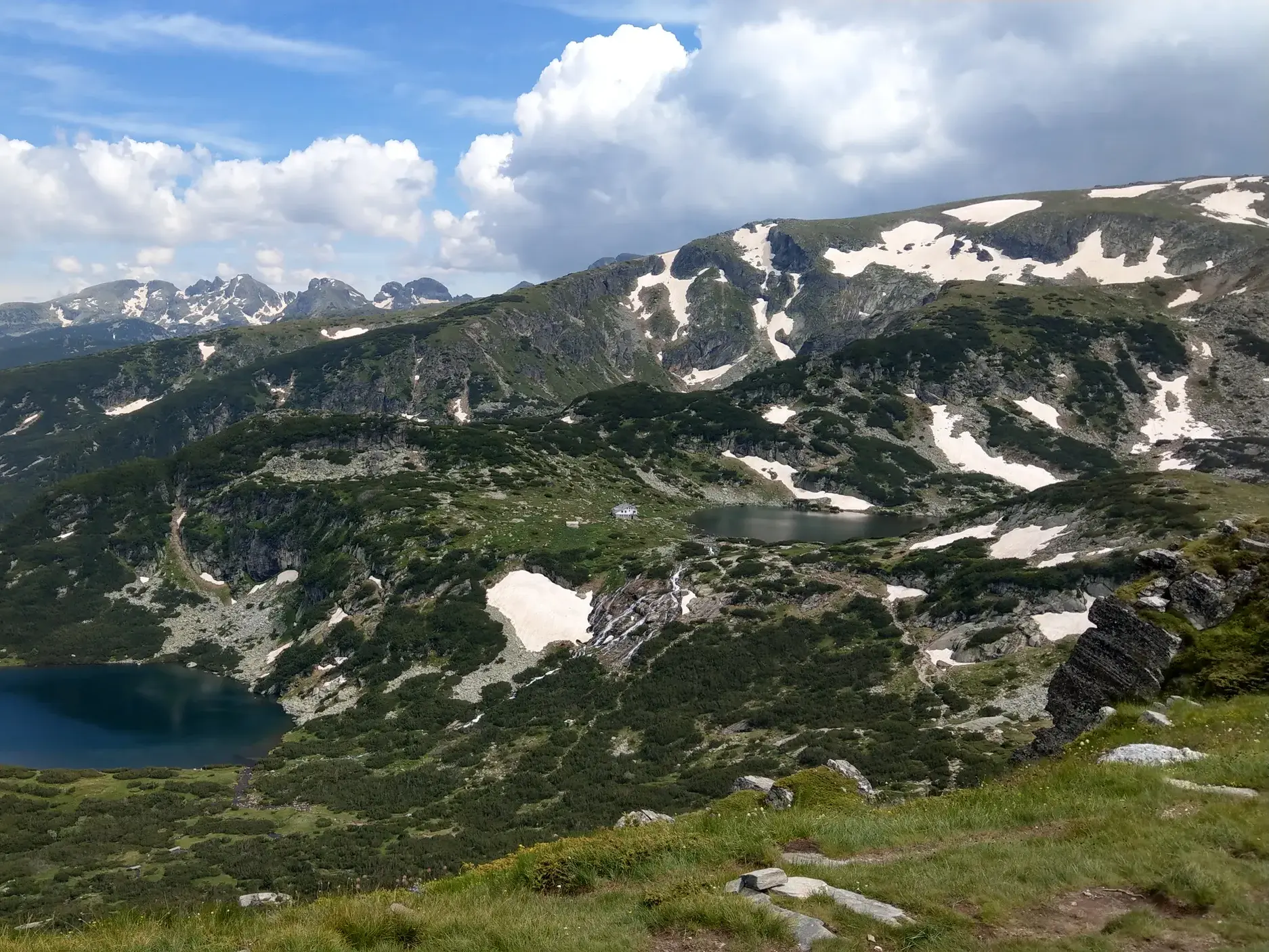 Aussicht beim Wandern auf die tiefblauen Bergseen und schneebedeckten Gipfel der berühmten Sieben Seen im Rila-Gebirge in Bulgarien.