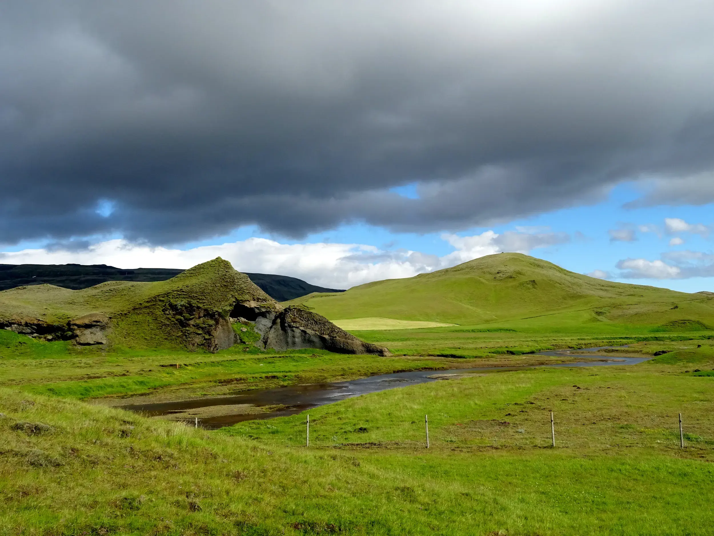 Bizarre, moosgrüne Felsformationen in der Vulkanlandschaft Eldgiá in Island unter dramatischem Himmel.