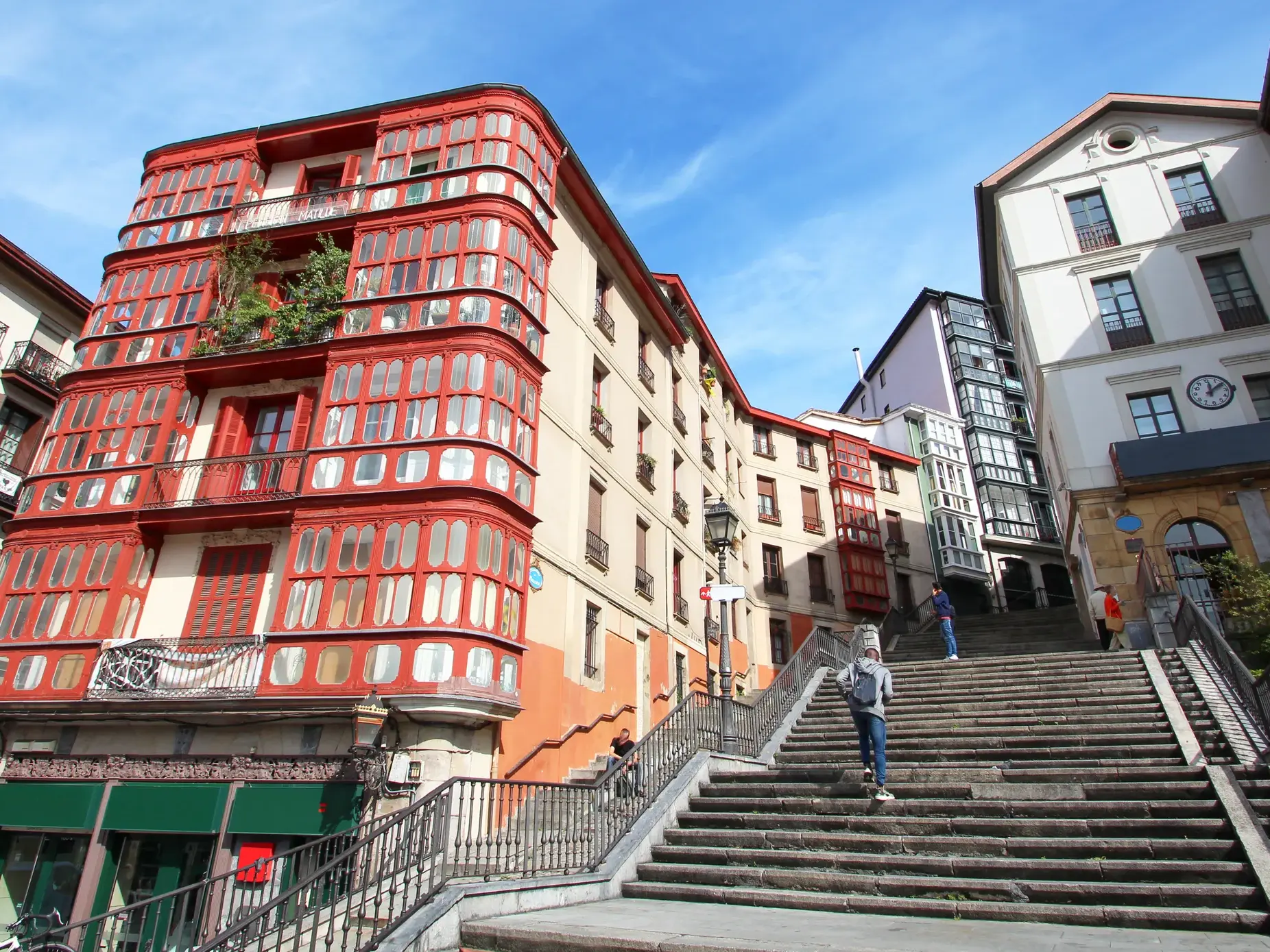 Steile Steintreppe in einer Gasse der Altstadt von Bilbao, gesäumt von einem markanten roten Haus mit Erkerfenstern.