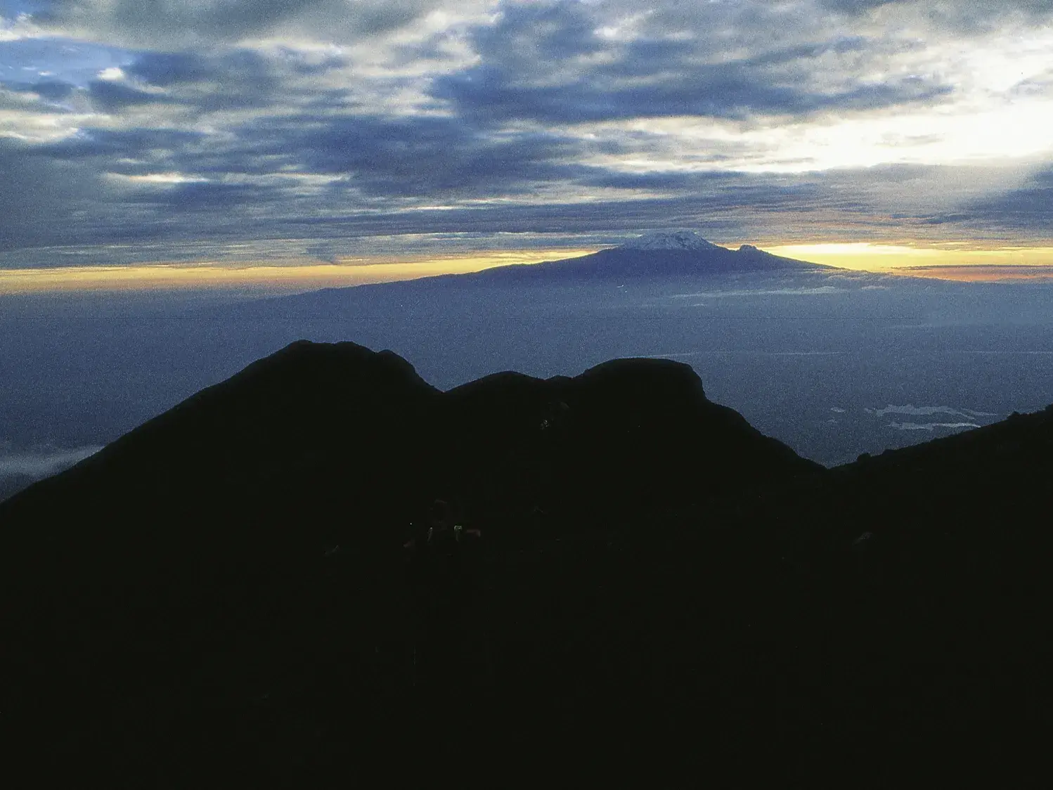 Spektakulärer Sonnenaufgang vom Gipfel des Mount Meru mit Blick auf den schneebedeckten Kilimanjaro und die Savanne Tansanias.