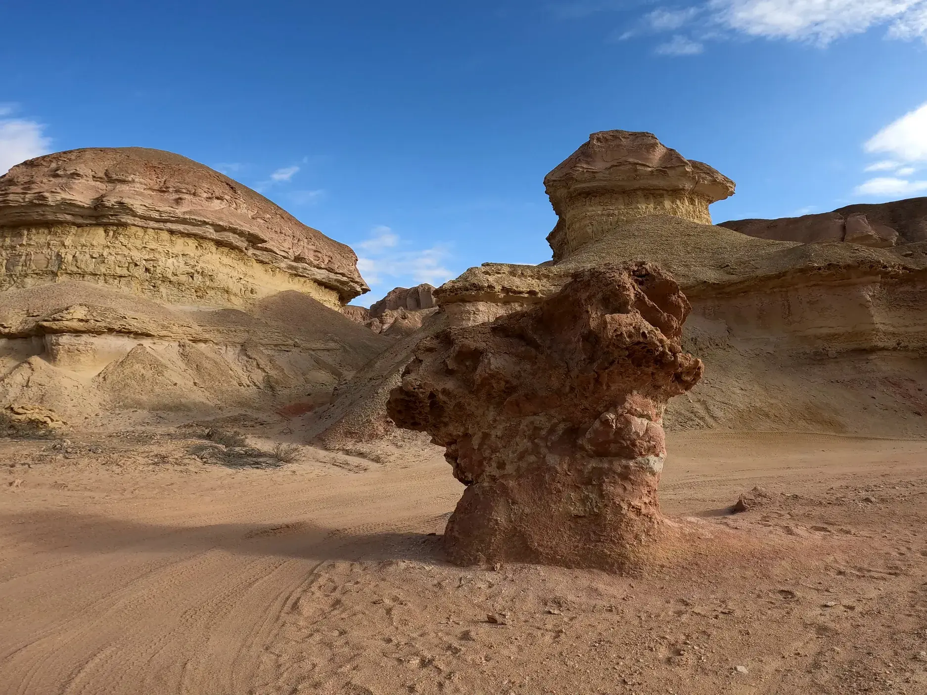 Rötliche, vom Wind geformte Sandsteintürme ragen in der weiten Wüstenlandschaft des Colinas Canyon in Angola auf.