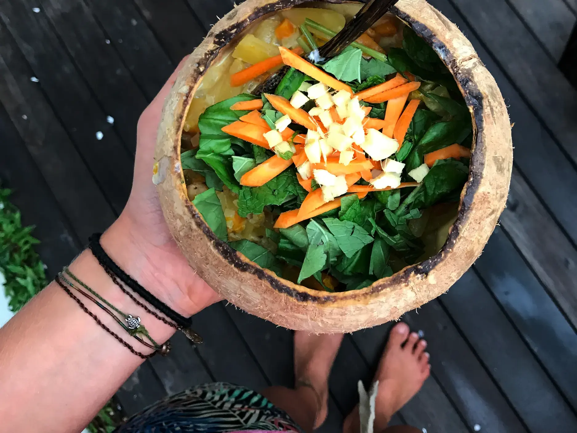 Ein frisch zubereitetes Curry aus dem Kochkurs in Ubud, serviert in einer Kokosnuss mit Karotten und frischen Kräutern.