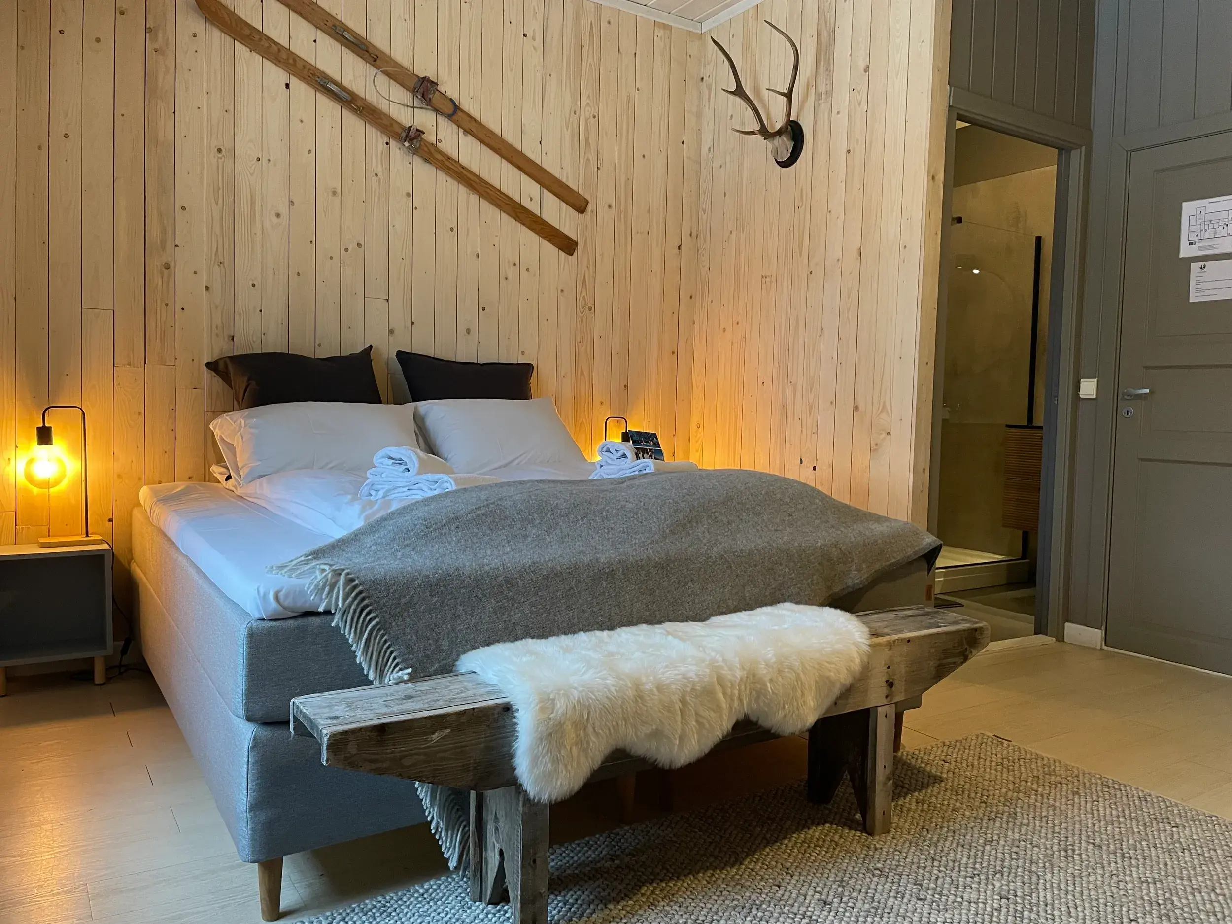 Einladendes Zimmer in der Harangtunet Mountain Lodge mit Holzwänden, dekorativen Skiern und Schaffell in der Region Valdres.