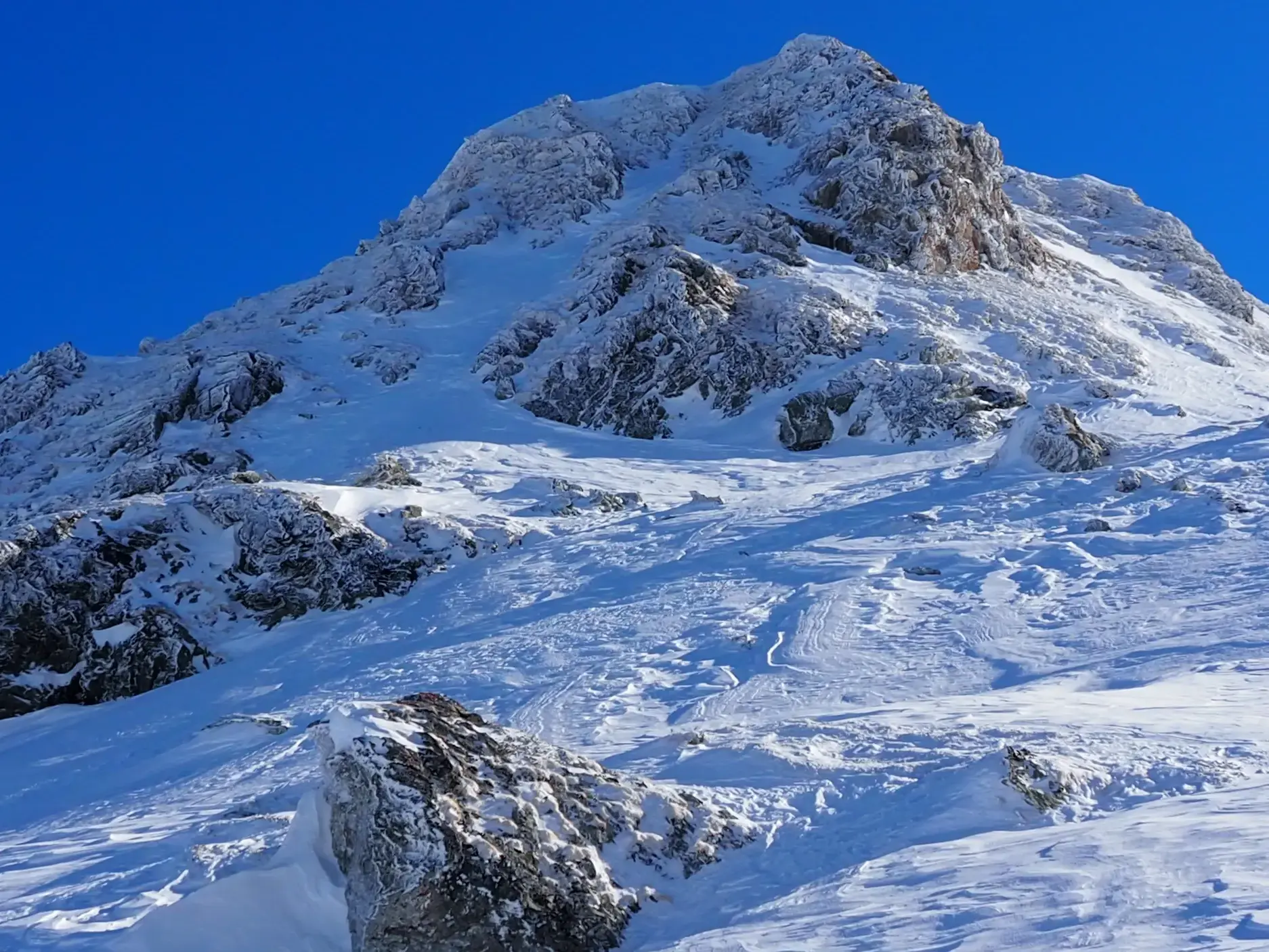 Der felsige Gipfel des Korab in Albanien, tief verschneit und bereit für die Abfahrt bei einer Skitour im Balkan.
