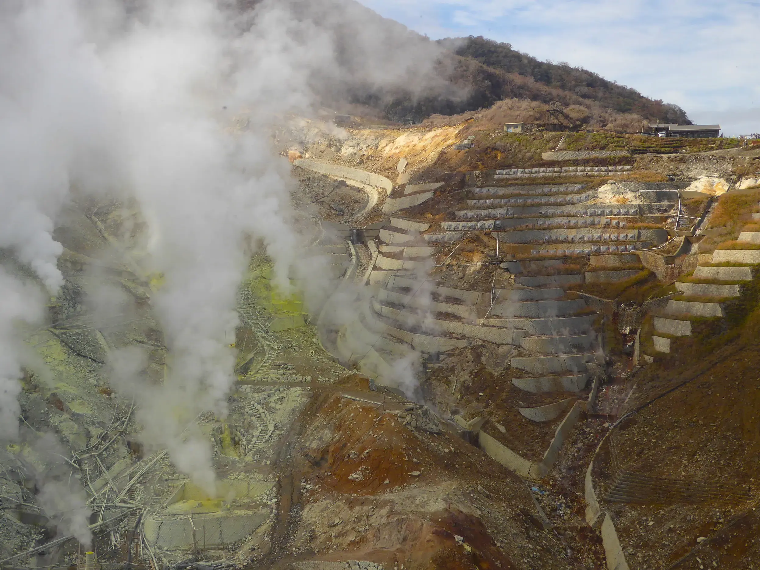 Dampfendes Schwefeltal Owakudani im Fuji-Hakone-Nationalpark mit terrassierten Hängen und gelben Schwefelablagerungen.