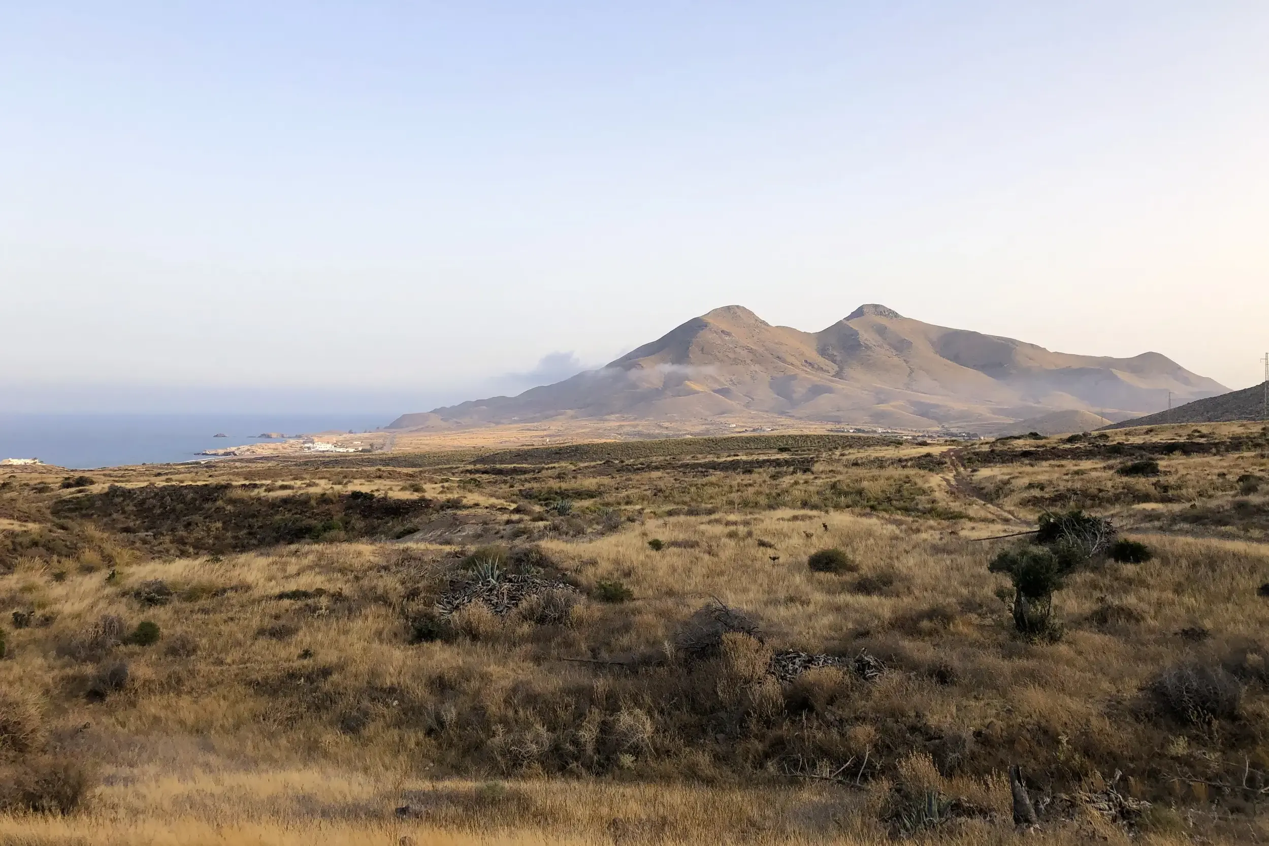 Ausblick über die steppenartige Vulkanlandschaft des Naturparks Cabo de Gata mit dem Mittelmeer und Küstengebirge.