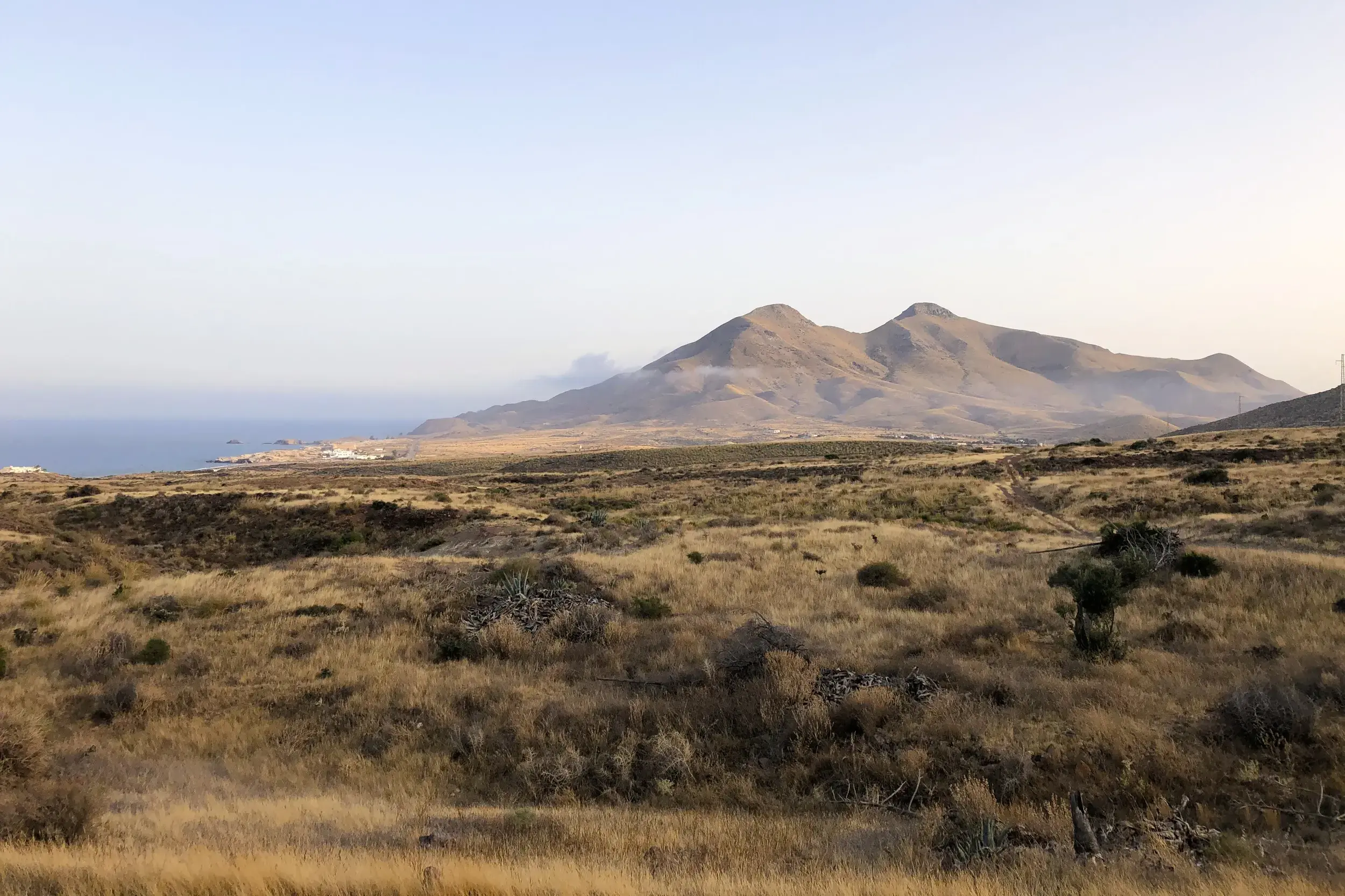 Ausblick über die steppenartige Vulkanlandschaft des Naturparks Cabo de Gata mit dem Mittelmeer und Küstengebirge.