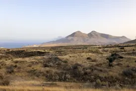 Ausblick über die steppenartige Vulkanlandschaft des Naturparks Cabo de Gata mit dem Mittelmeer und Küstengebirge.