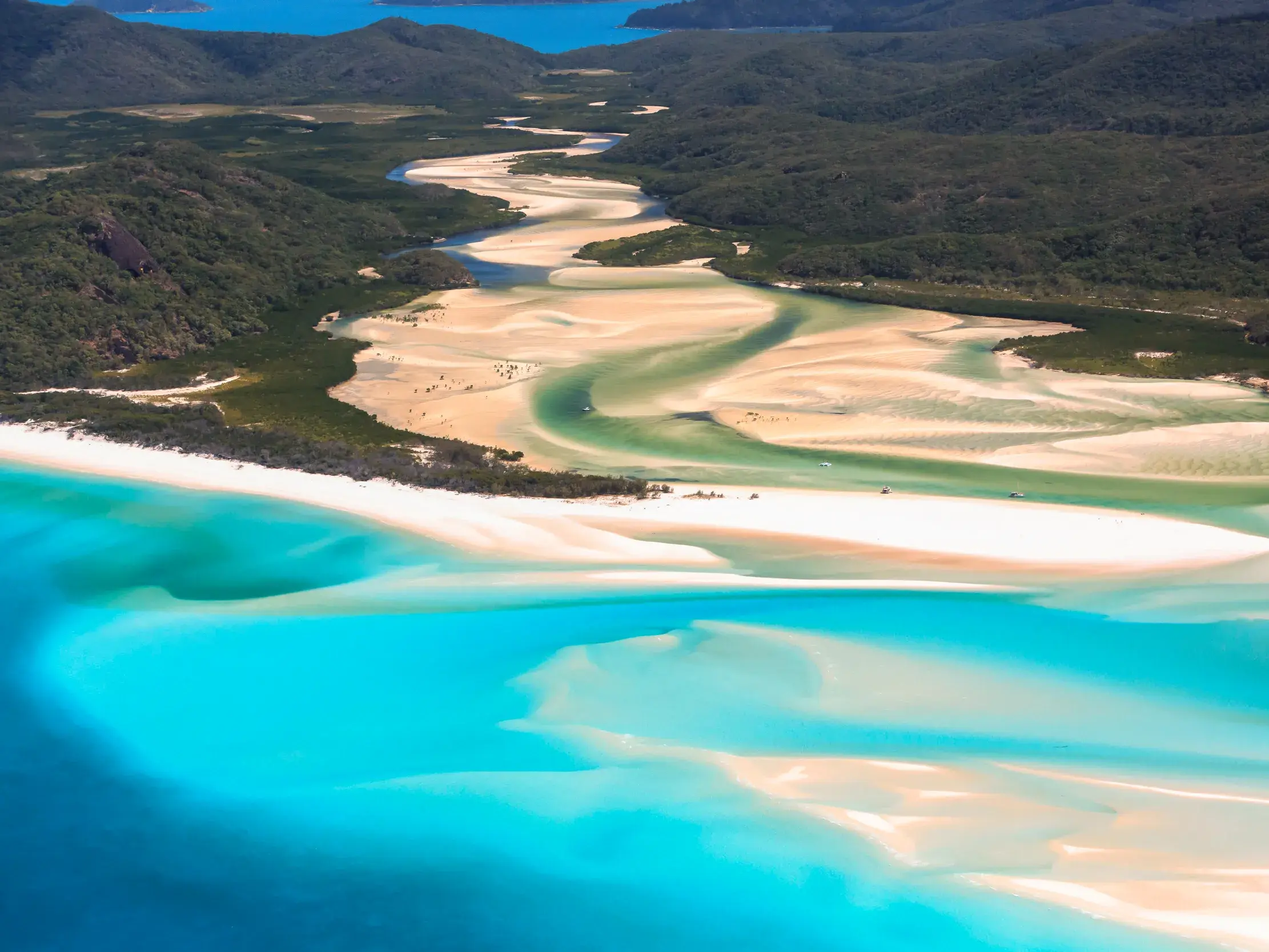 Luftaufnahme vom Whitehaven Beach auf den Whitsundays mit türkisfarbenem Wasser und weißen Sandwirbeln am Hill Inlet.