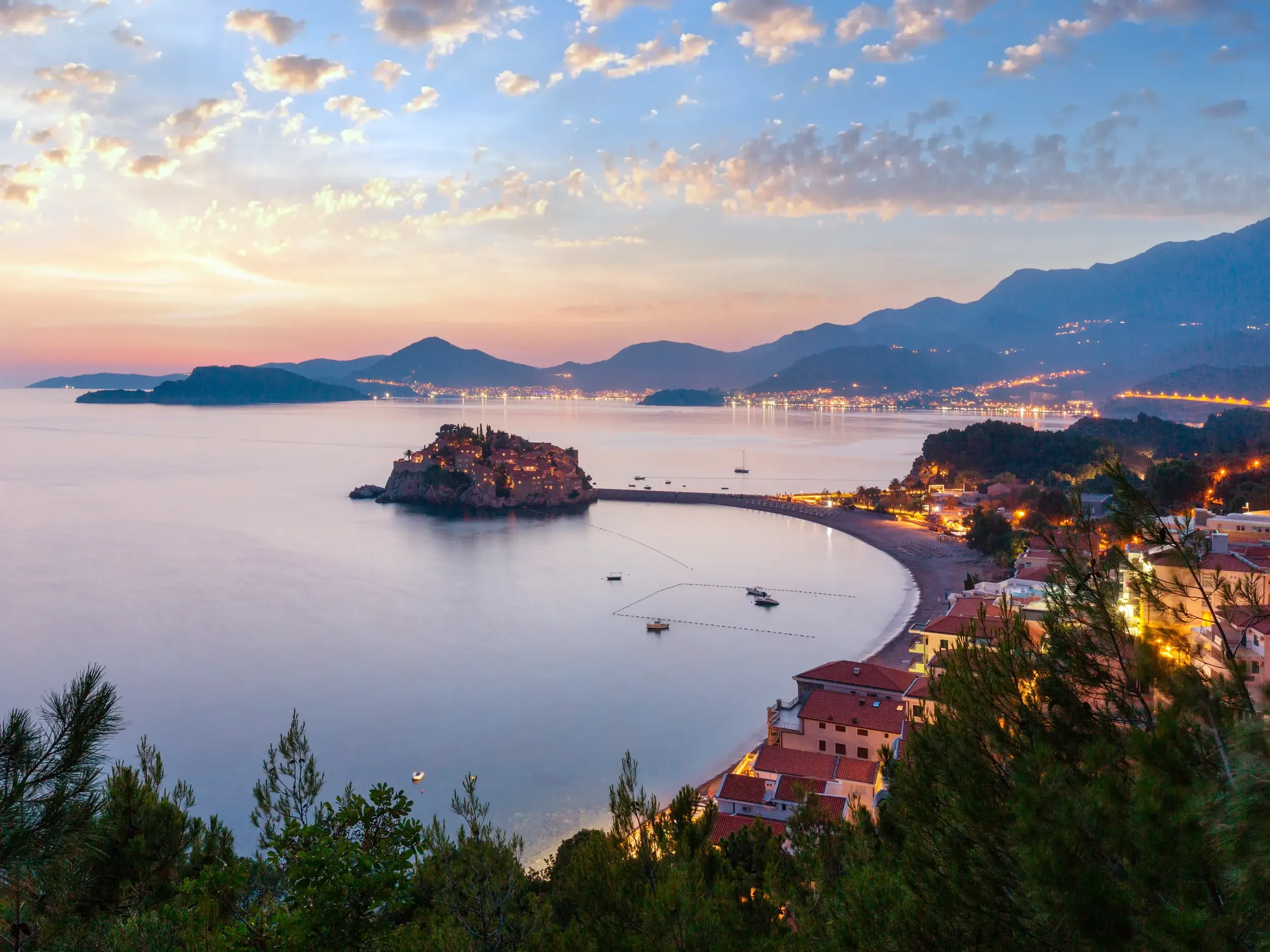 Malerische Abenddämmerung an der Küste Montenegros mit Blick auf die beleuchtete Halbinsel Sveti Stefan nahe Budva.