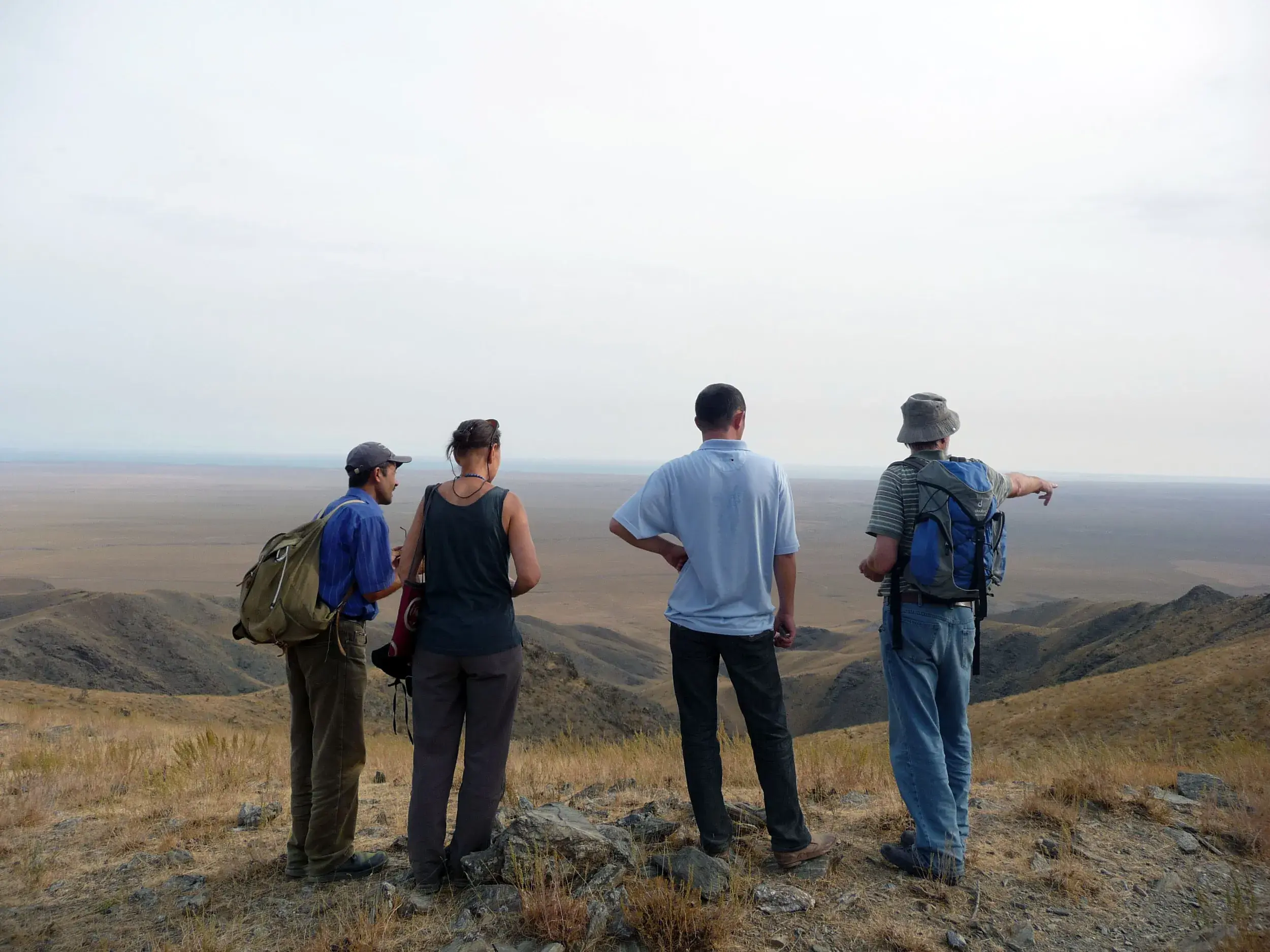 Eine Hauser-Wandergruppe mit Reiseleiter genießt auf einem Bergplateau im Nuratau-Gebirge den Panoramablick über die Weite.