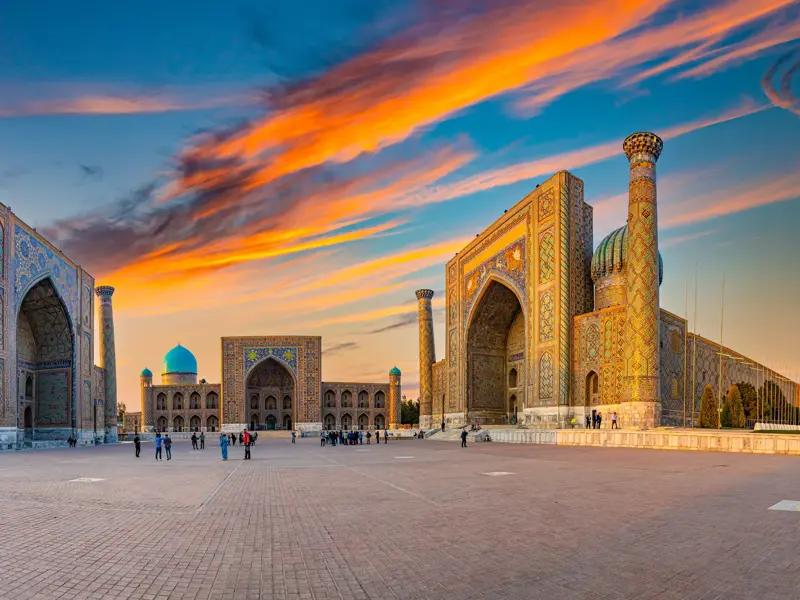 Magischer Sonnenuntergang über dem Registan-Platz in Samarkand mit seinen prachtvollen, blau gekachelten Medresen.