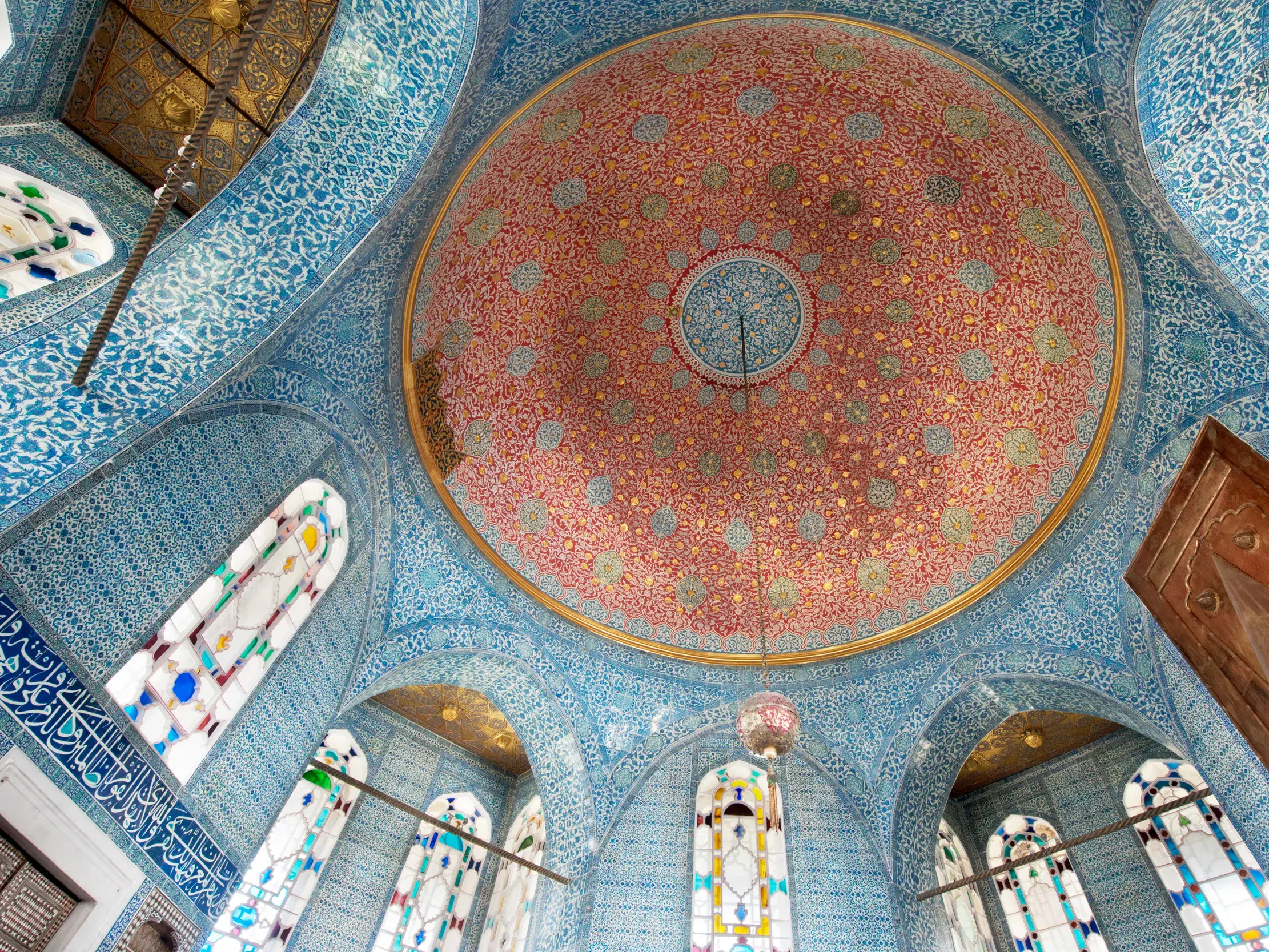 Prunkvolle rote Kuppel umgeben von blauen, ornamentalen Kacheln im Harem des Topkapi-Palastes in Istanbul.