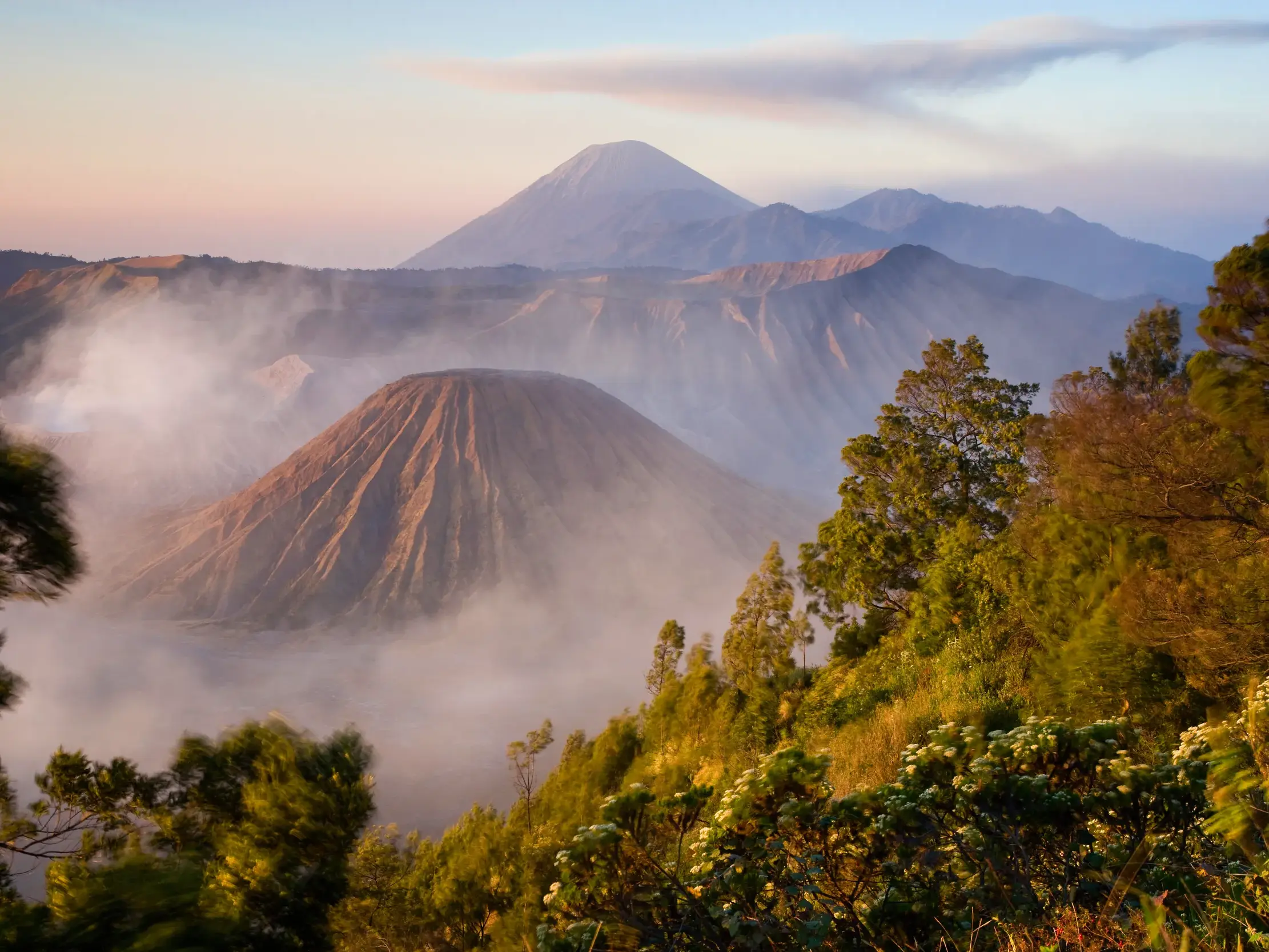 Majestätischer Sonnenaufgang am Vulkan Bromo auf Java, dessen rauchender Krater aus dem nebligen Tal im Morgenlicht emporragt.