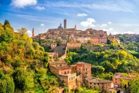 Panoramablick auf die mittelalterliche Stadt Siena in der Toskana mit ihrem Dom, umgeben von grünen Hügeln an einem sonnigen Tag.