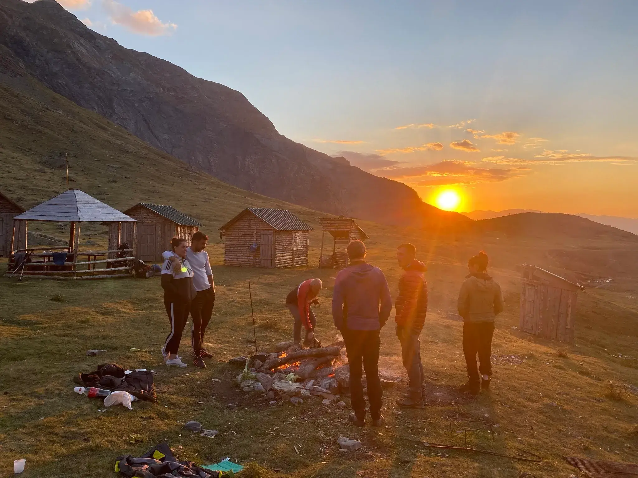 Reisegruppe am Lagerfeuer bei den Schäferhütten auf der Grama-Alm während des Sonnenuntergangs in den albanischen Bergen.