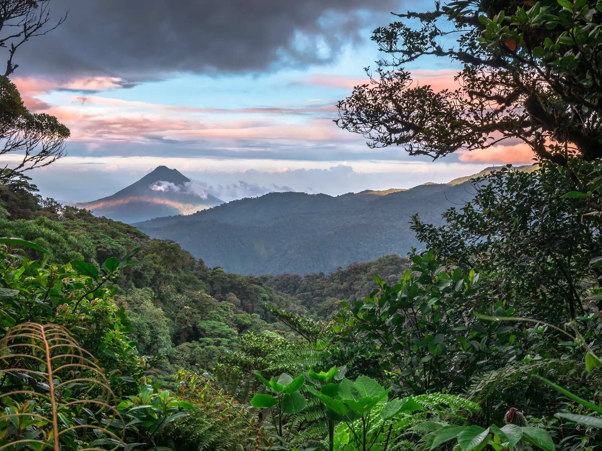 Der Vulkan Arenal erhebt sich über dem dichten Regenwald Costa Ricas bei einem farbenfrohen Sonnenuntergang im Nebelwald.