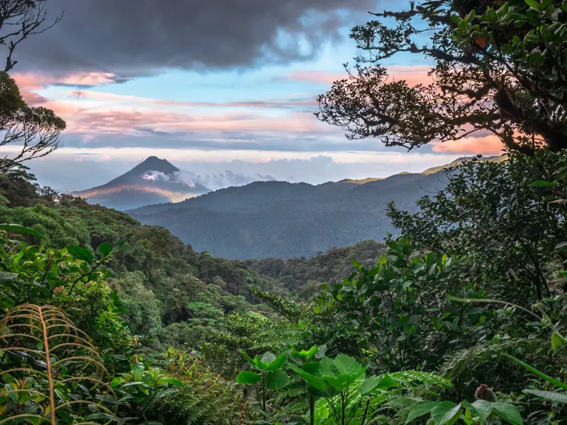 Der Vulkan Arenal erhebt sich über dem dichten Regenwald Costa Ricas bei einem farbenfrohen Sonnenuntergang im Nebelwald.