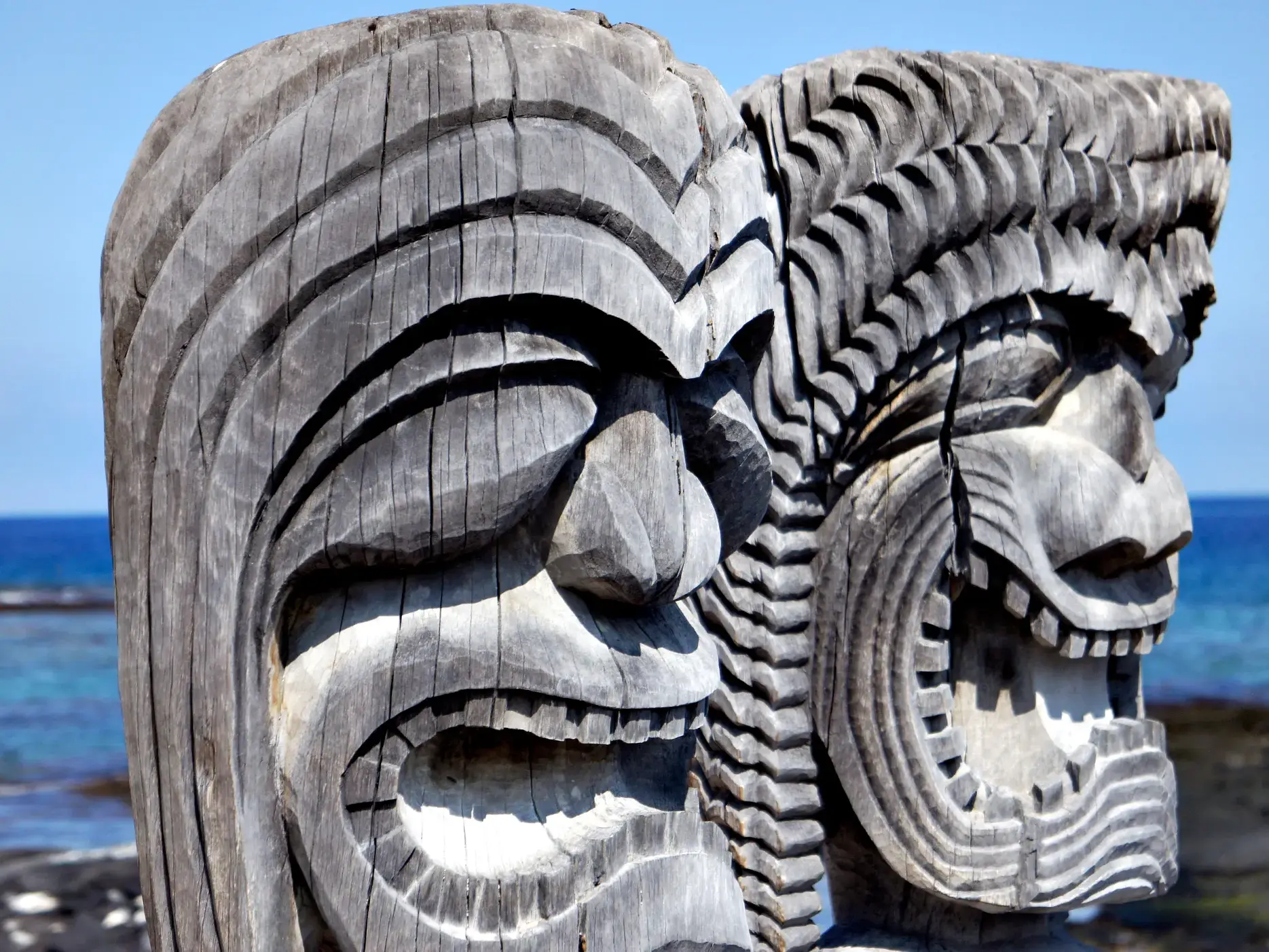 Zwei traditionelle, hölzerne Kii-Statuen wachen über die Küste im Puuhonua-o-Honaunau National Historical Park auf Hawaii.