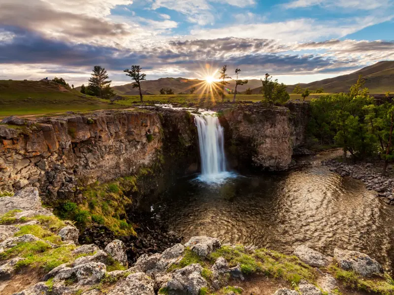 Der malerische Orkhon-Wasserfall stürzt bei Sonnenuntergang über eine Felsklippe in die weite Steppenlandschaft der Mongolei.