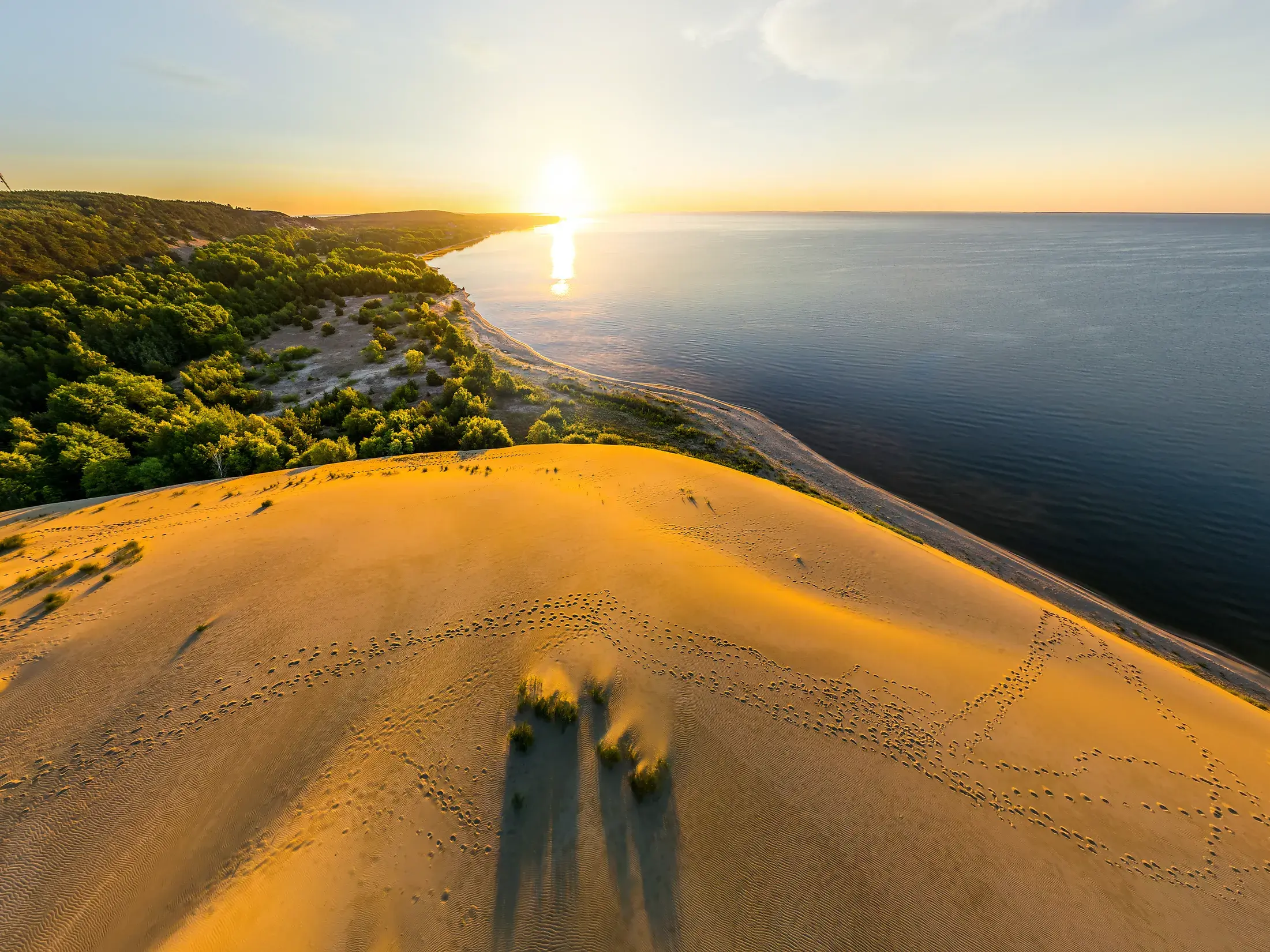 Goldener Sonnenuntergang von der Hohen Düne auf der Kurischen Nehrung mit weitem Blick über Sand, Wald und die Ostsee.