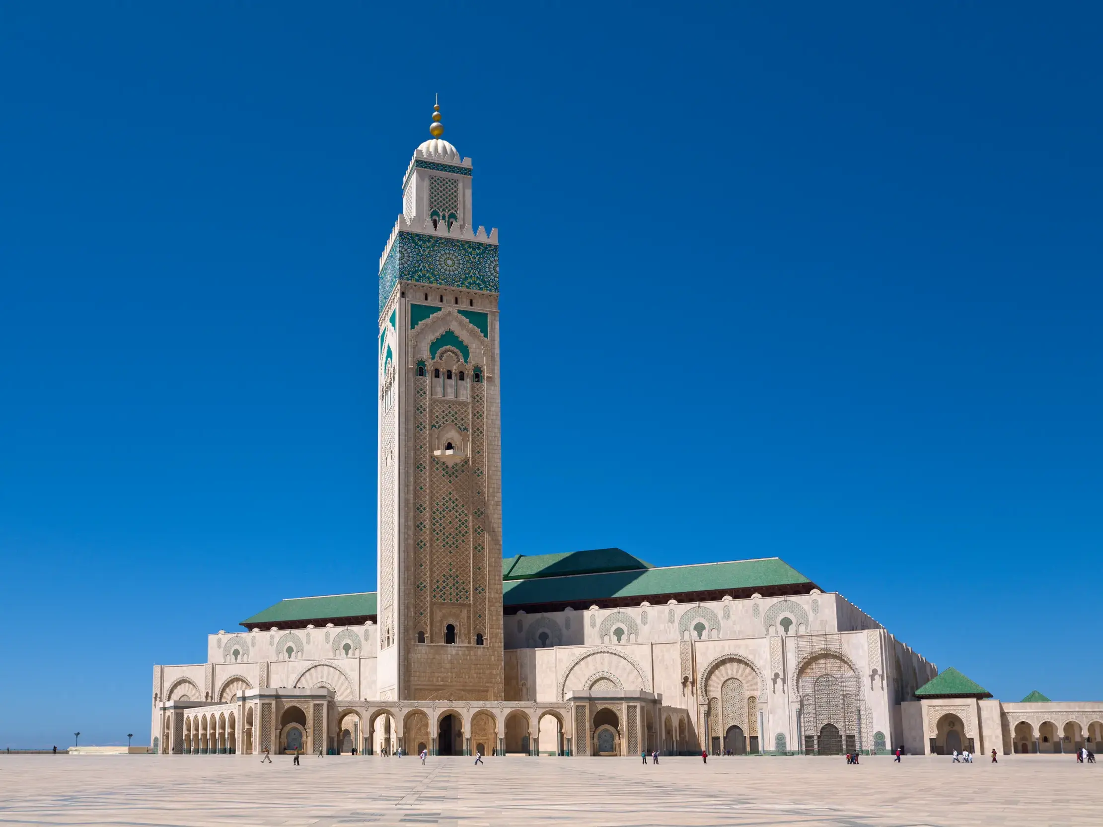 Die monumentale Hassan-II.-Moschee in Casablanca mit ihrem hohen Minarett unter einem tiefblauen Himmel am Atlantik.