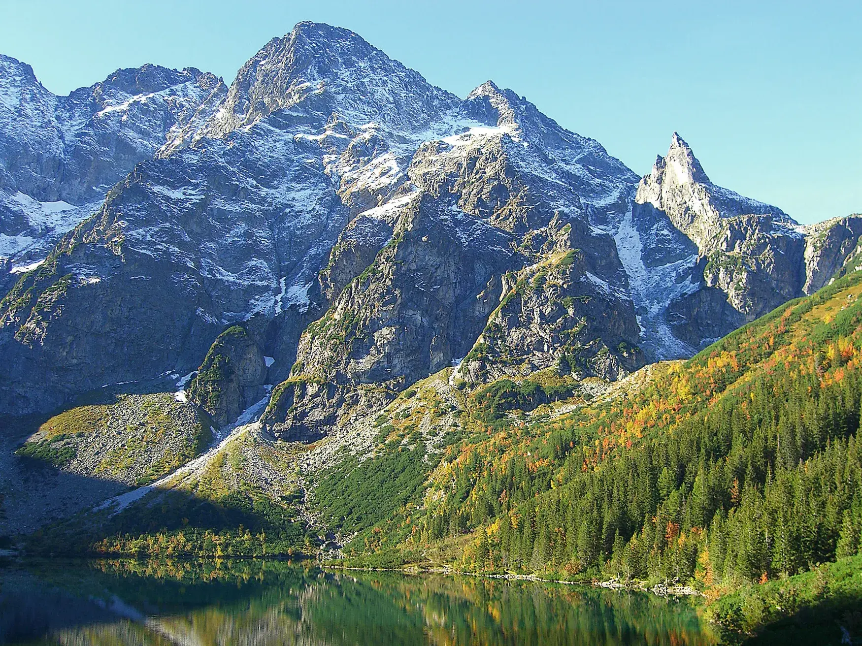 Die schneebedeckten Gipfel der Hohen Tatra spiegeln sich im glasklaren Wasser des Bergsees Popradske Pleso in der Slowakei.