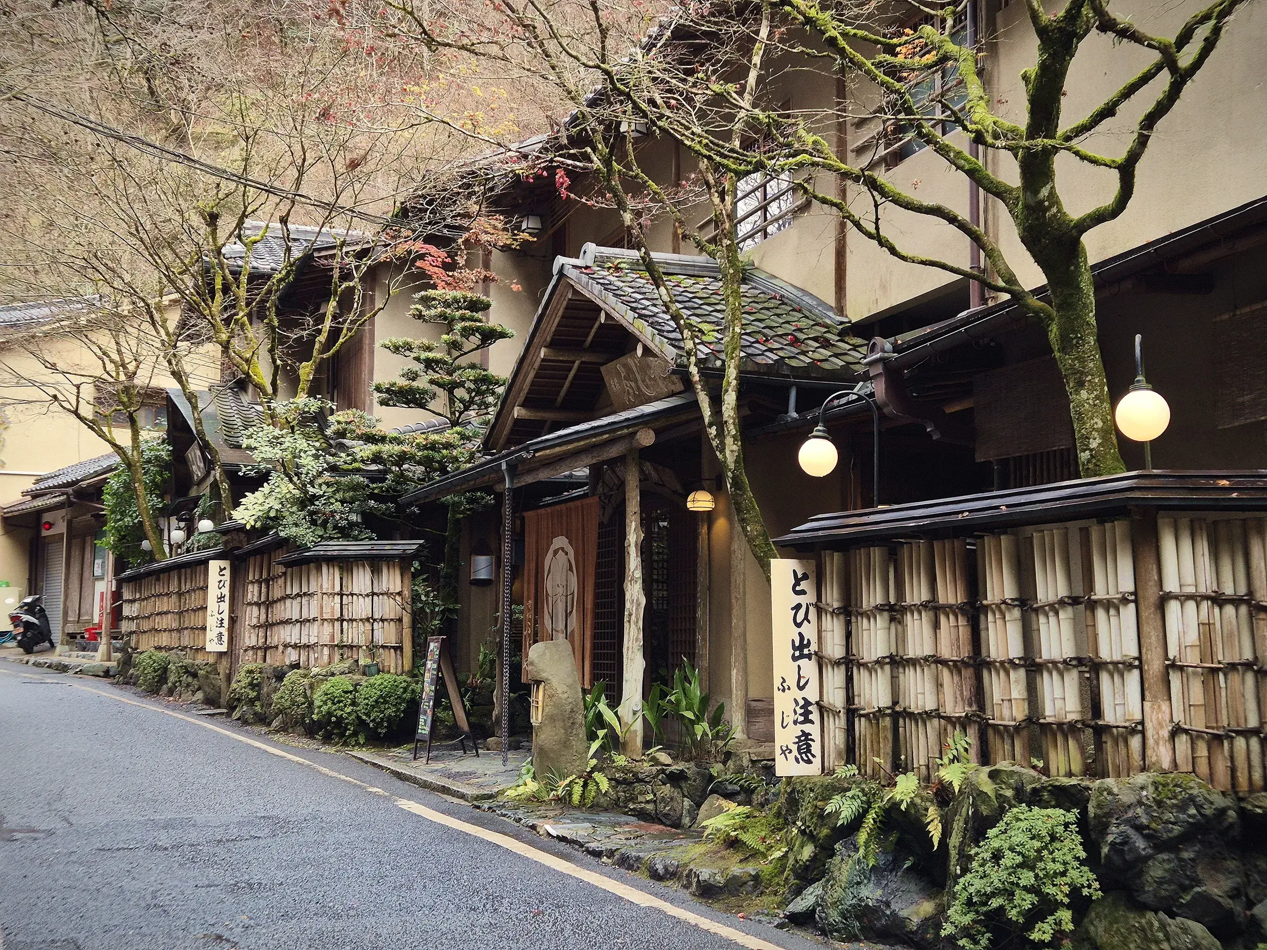 Traditionelle japanische Häuser mit Bambuszäunen und Laternen säumen eine Gasse im historischen Gion-Viertel in Kyoto.